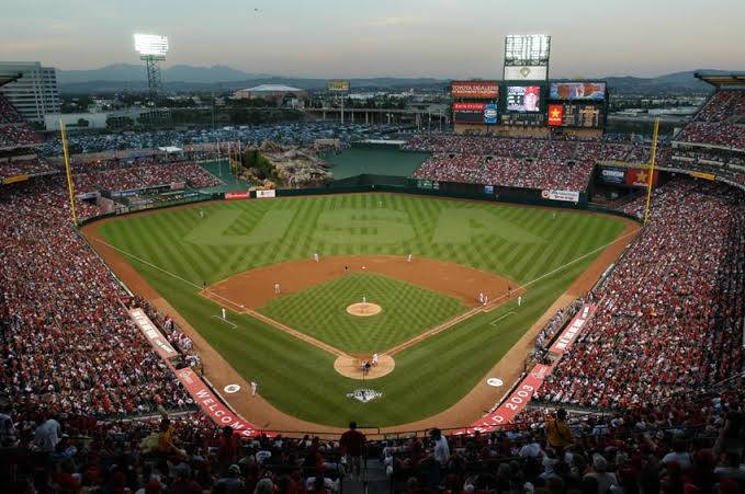 MLB比分：安那罕天使球場 壁紙 — 黃昏時分，一個座無虛席的棒球場，球迷們歡呼著，球員們在精心維護的場地上比賽。