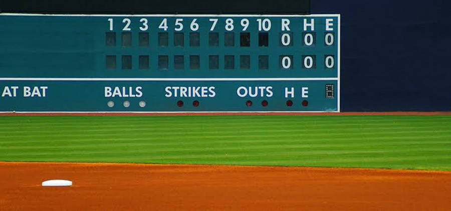MLB比分板 壁紙 — 棒球計分板特寫，顯示零得分、安打和出局，前景是純淨的綠色球場和棕色泥土。
