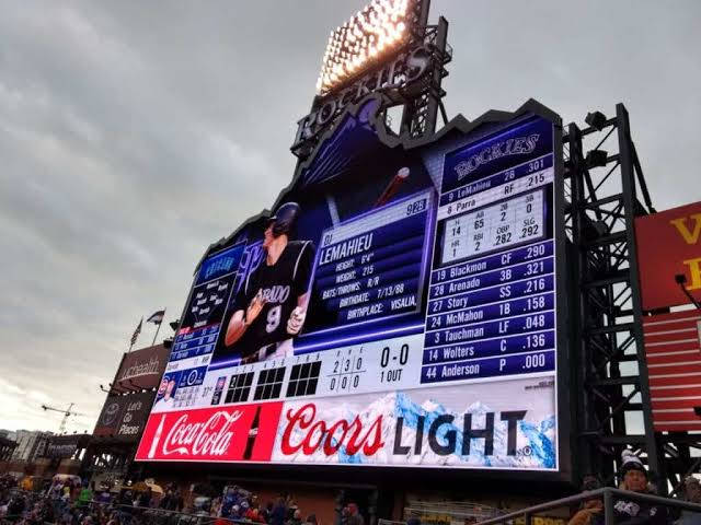 MLB比分與廣告標誌 壁紙 — 庫爾斯球場的巨大記分板在陰天和球場燈光下顯示球員統計數據和比賽資訊。