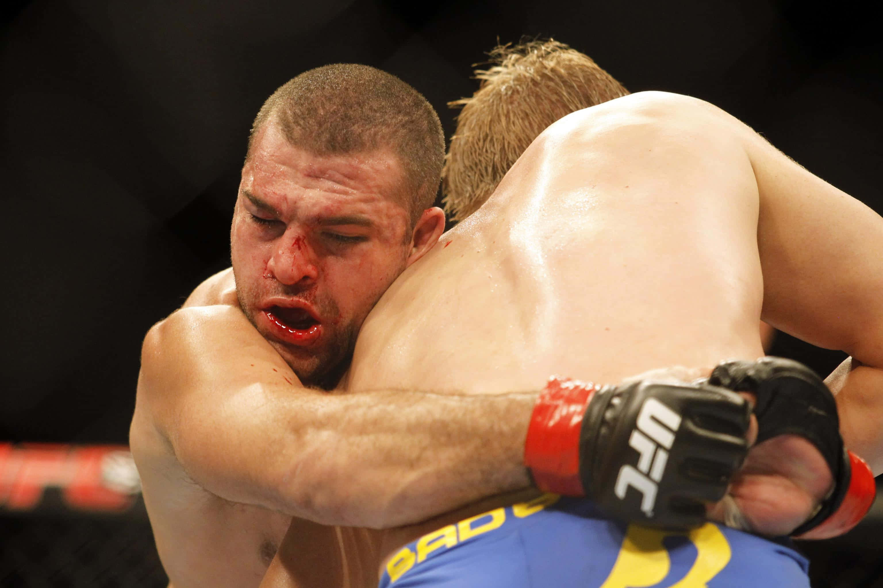 傳奇MMA選手傑瑞米·霍恩 壁紙 — 兩名拳手在UFC八角籠中激烈纏鬥，其中一名拳手鼻子和嘴巴流血。