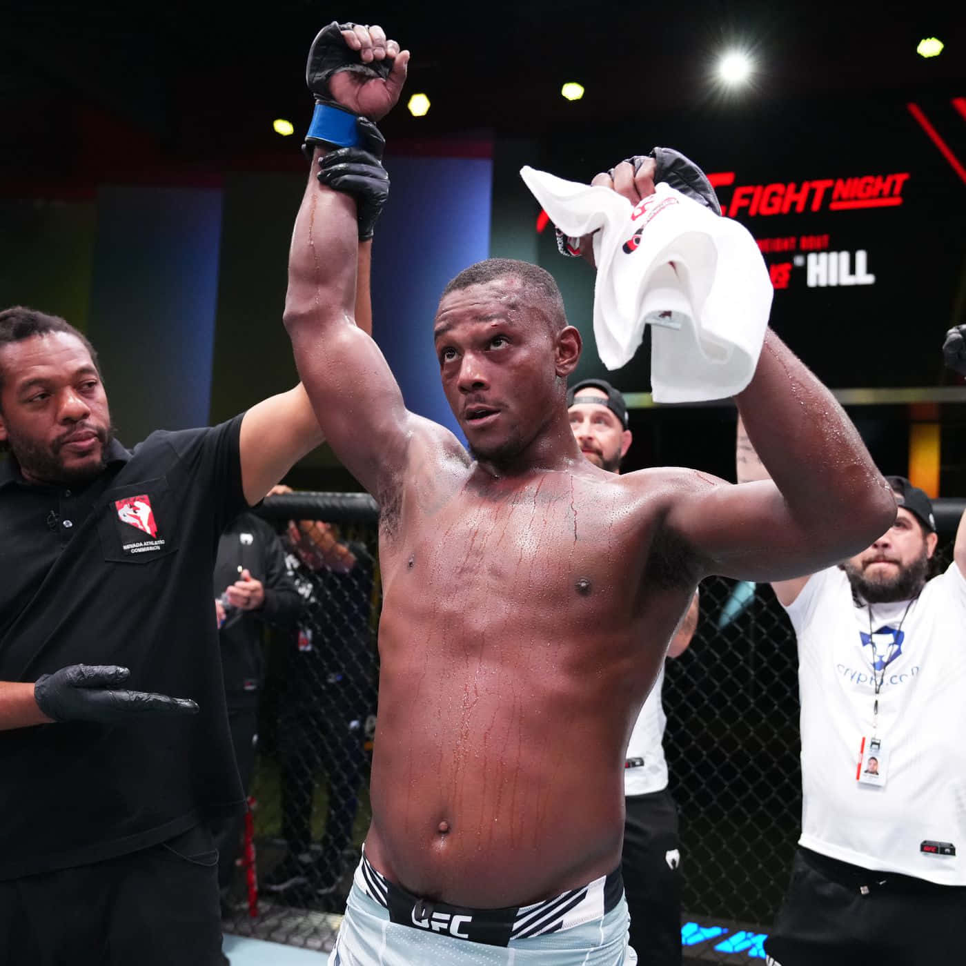 UFC拳手與教練和人群在八角籠中慶祝勝利。