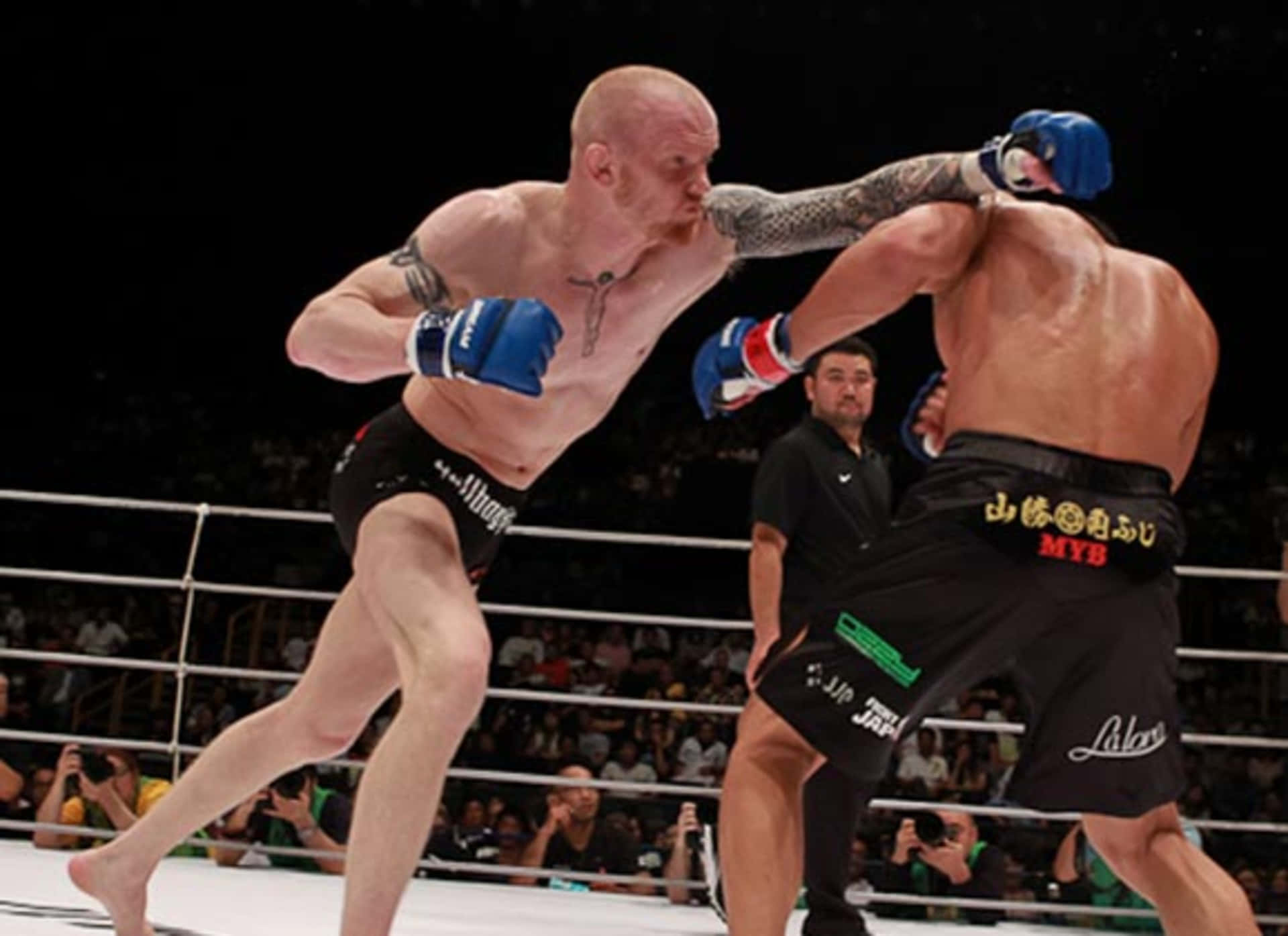 MMA選手喬希姆·漢森與田上達也於Dream 17賽事中的激烈對決 壁紙 — 一名拳手在燈光明亮的MMA擂台上，向對手施展強力肘擊，觀眾正在觀看。