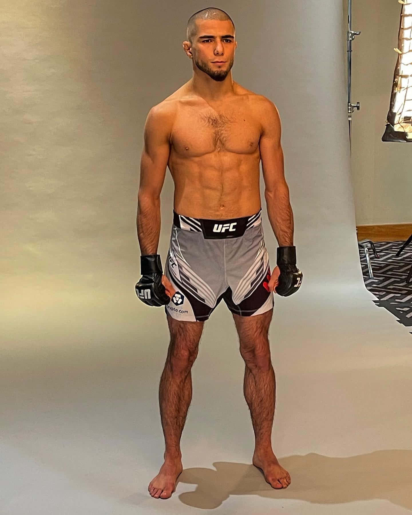 運動型男性拳手穿著UFC短褲和手套在攝影棚中擺姿勢。