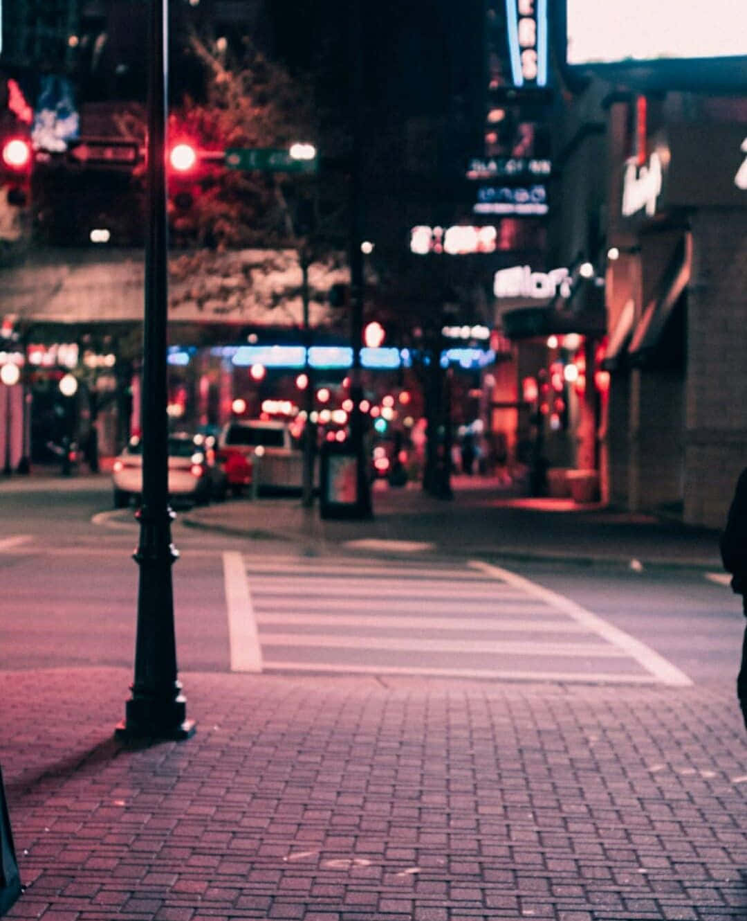 夜間城市街道，有發光的霓虹燈招牌和紅色交通燈。