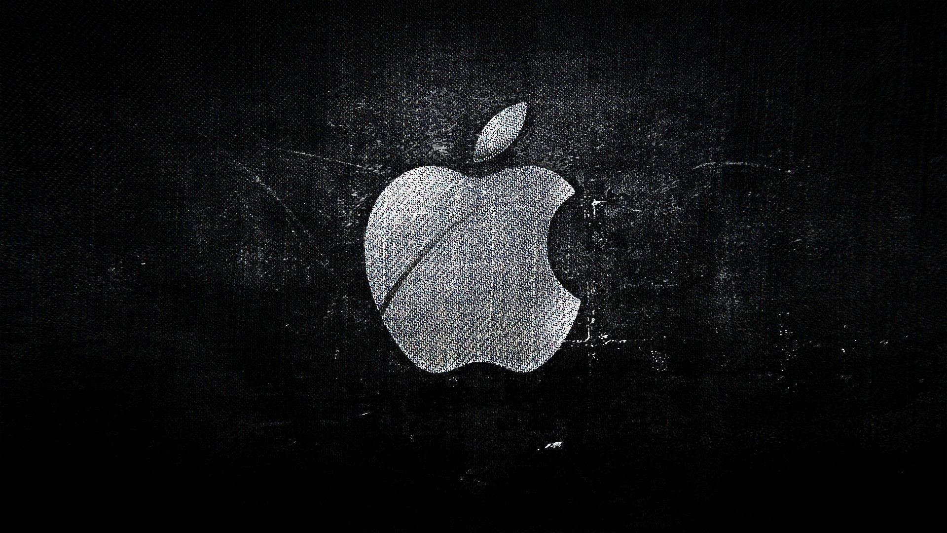 紋理蘋果標誌黑色Mac 壁紙 — 一個磨損的銀色Apple標誌在帶有刮痕和顆粒的紋理黑色背景上發光。