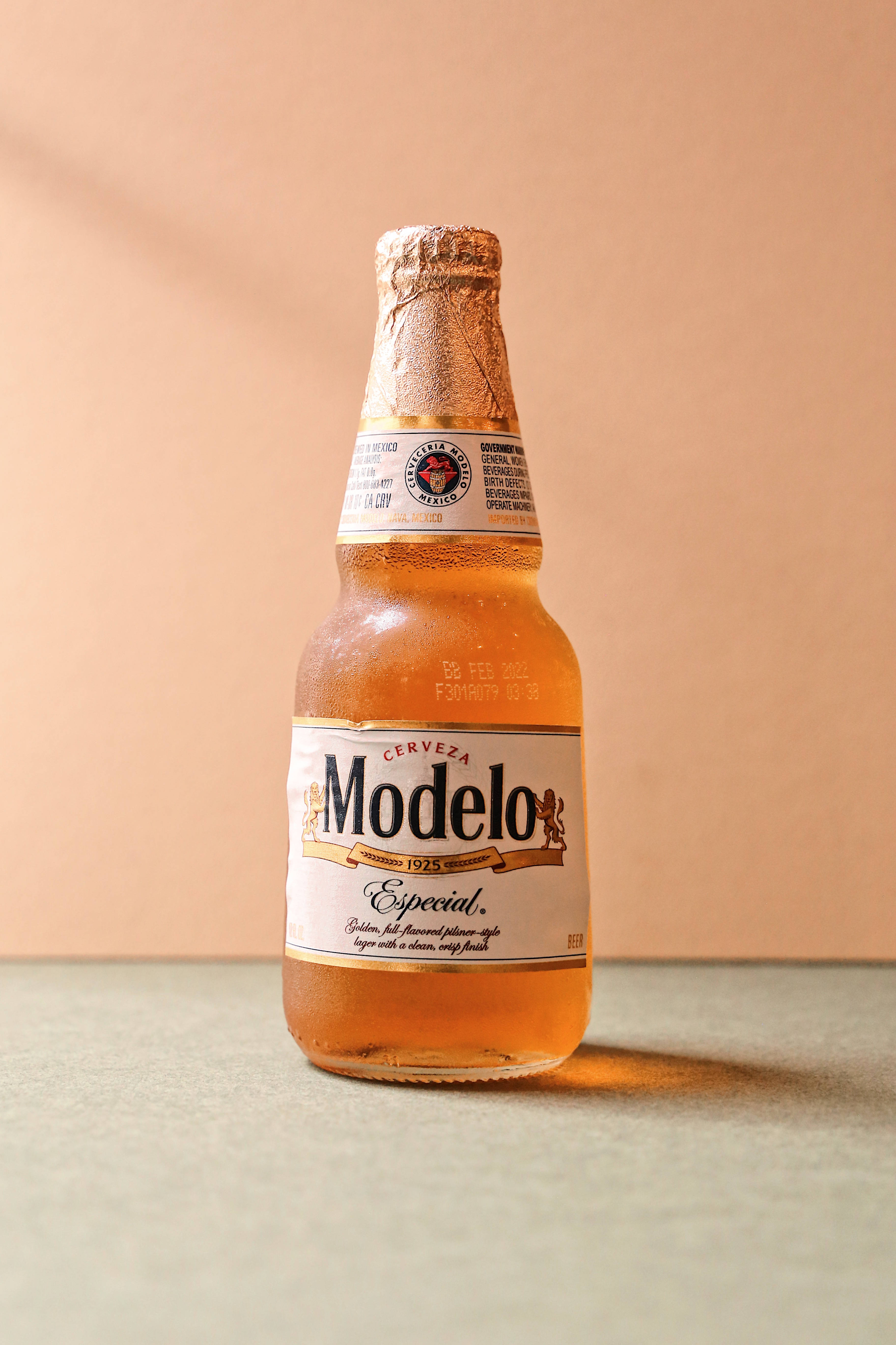 冰鎮Modelo Especial啤酒瓶 壁紙 — 冰凍的Modelo Especial啤酒瓶在溫暖的桃色背景下閃爍著冷凝水珠。
