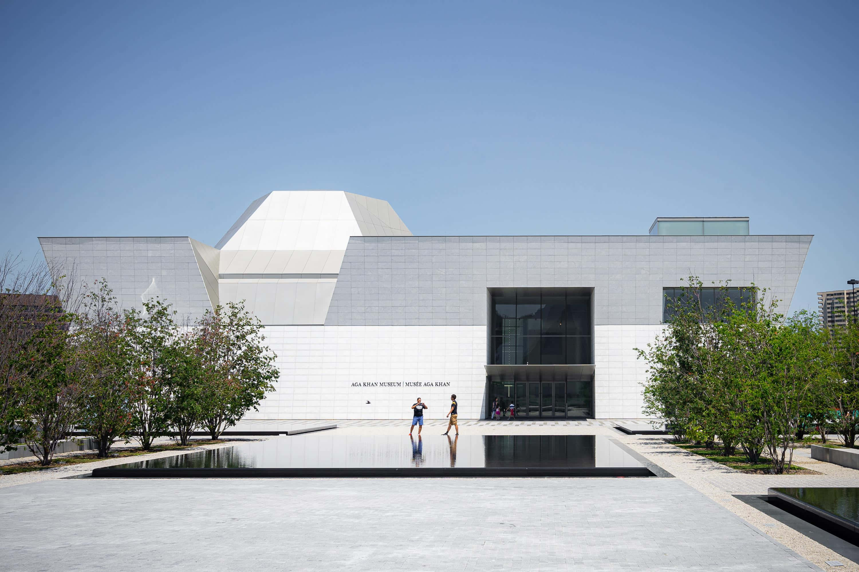 Aga Khan Museum 桌布 壁紙 — 現代白色幾何博物館，玻璃外牆和倒影池，在清澈藍天下。