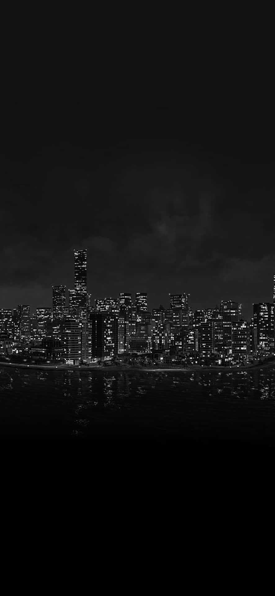 夜間城市景觀，發光的建築物倒映在烏雲下的水中。