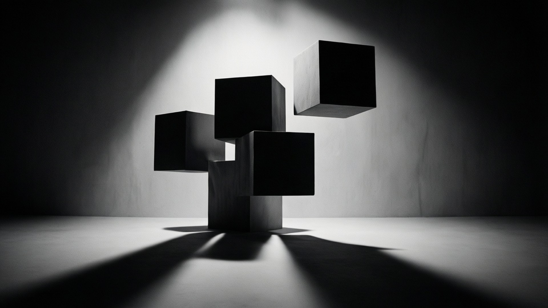 Monochrome Cube Shadows 壁紙 — 五個啞光黑色立方體在強烈的聚光燈下漂浮和堆疊，背景是漸變灰色牆壁，投射出戲劇性的陰影。