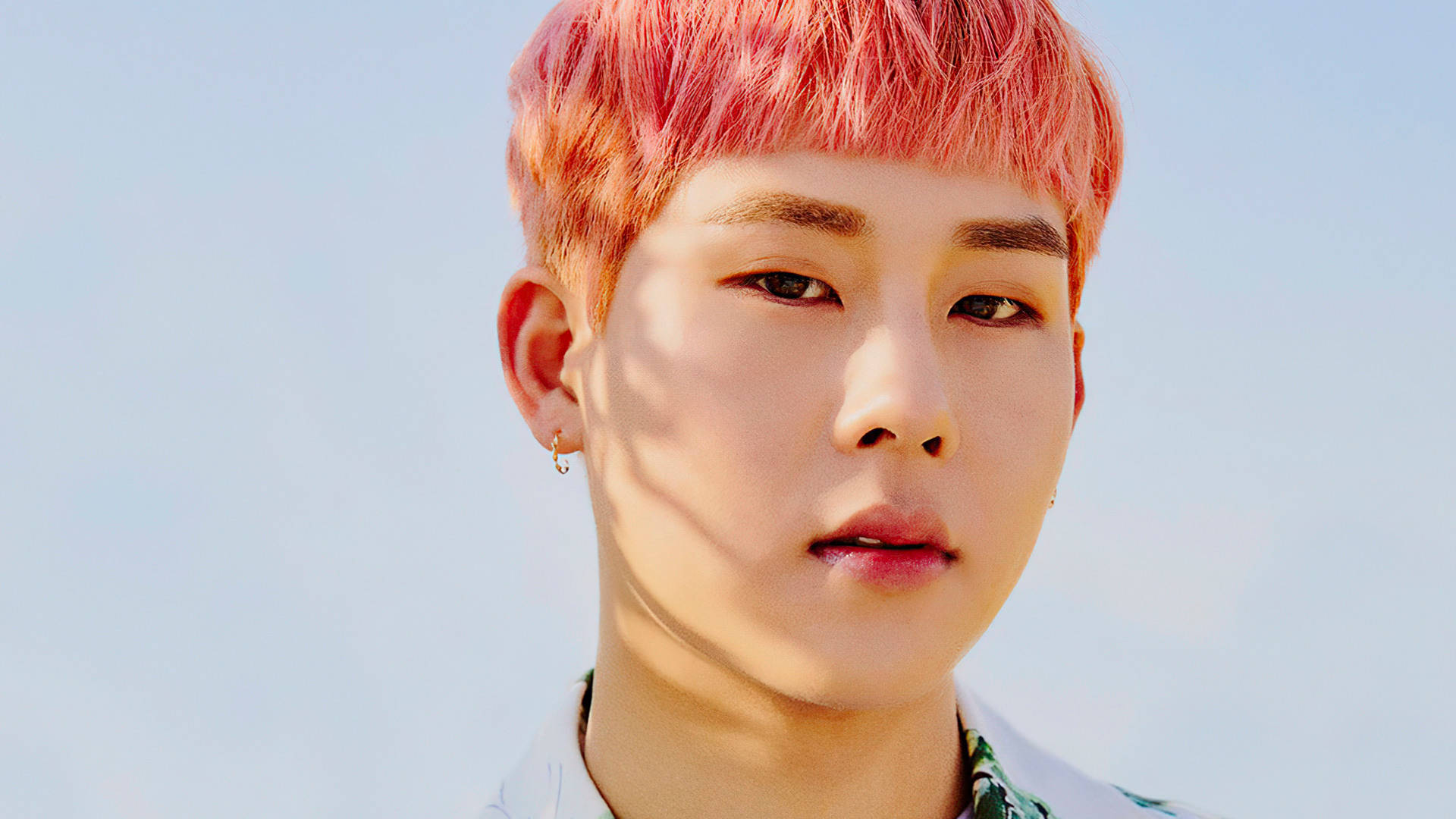 Monsta X Joohoney 粉髮造型 壁紙 — 一位年輕男子擁有鮮豔的粉紅色頭髮，在明亮的陽光下平靜地凝視著清澈的藍天。