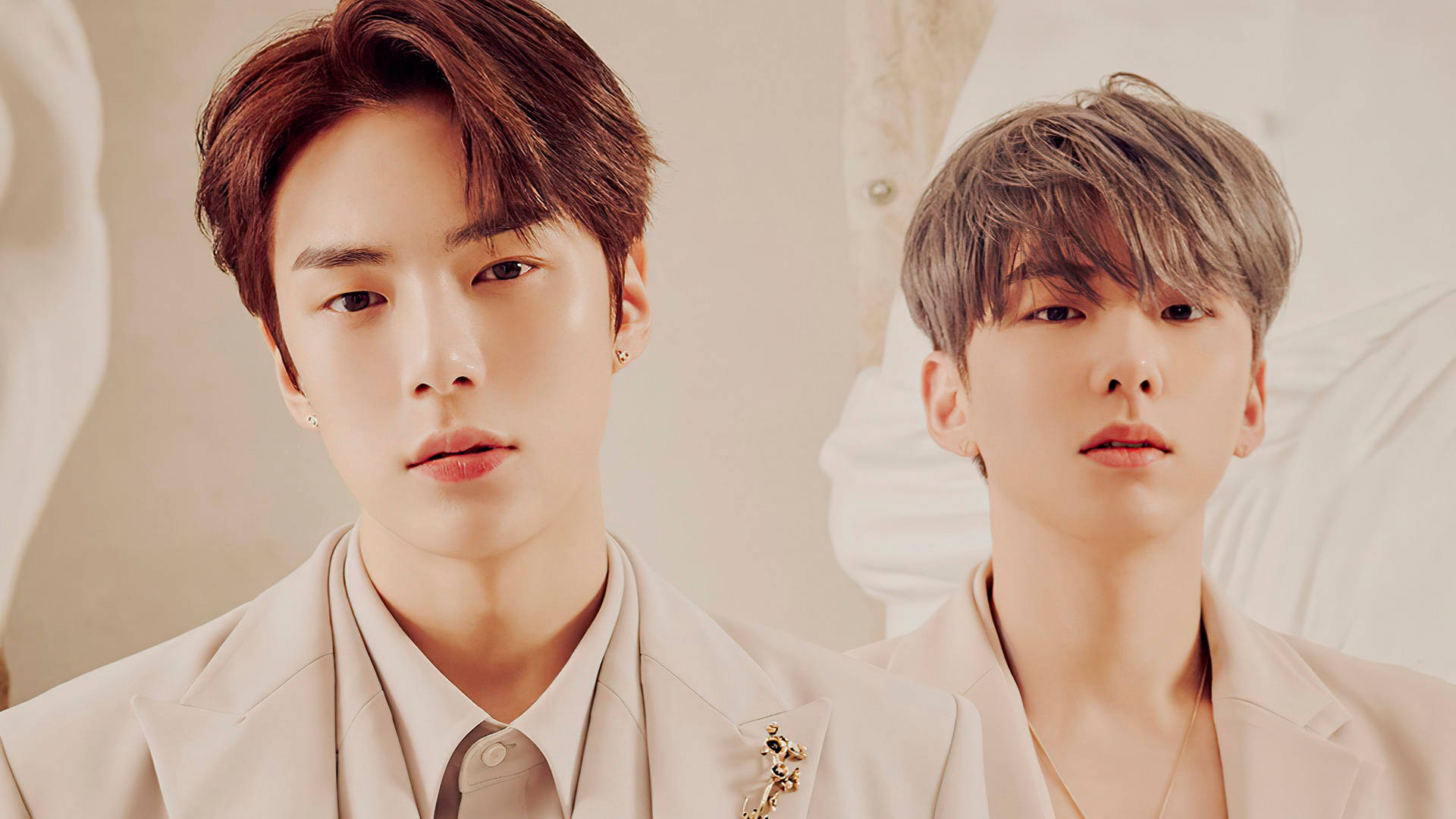 Monsta X Kihyun 與 Minhyuk 壁紙 — 兩位時尚年輕男士身穿米色西裝，在柔軟紋理背景前擺出嚴肅表情。