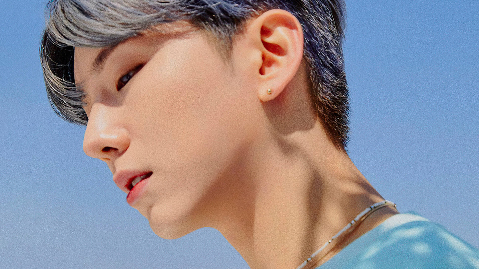 Monsta X Kihyun 日光下 壁紙 — 年輕男子灰髮金耳環的頭像特寫，背景為清澈藍天。