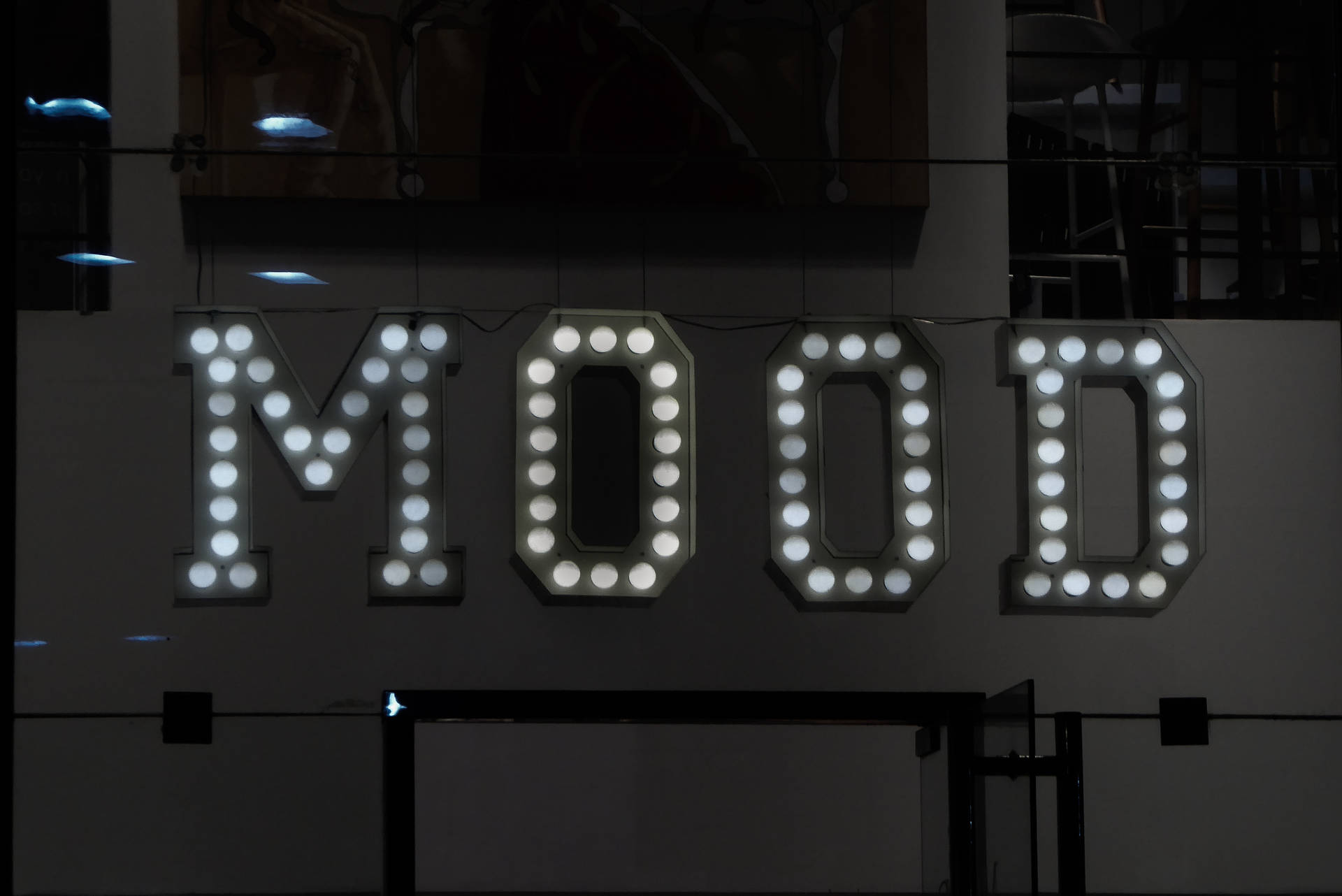 在黑暗的城市環境中，發光的白色字母標誌拼出MOOD。
