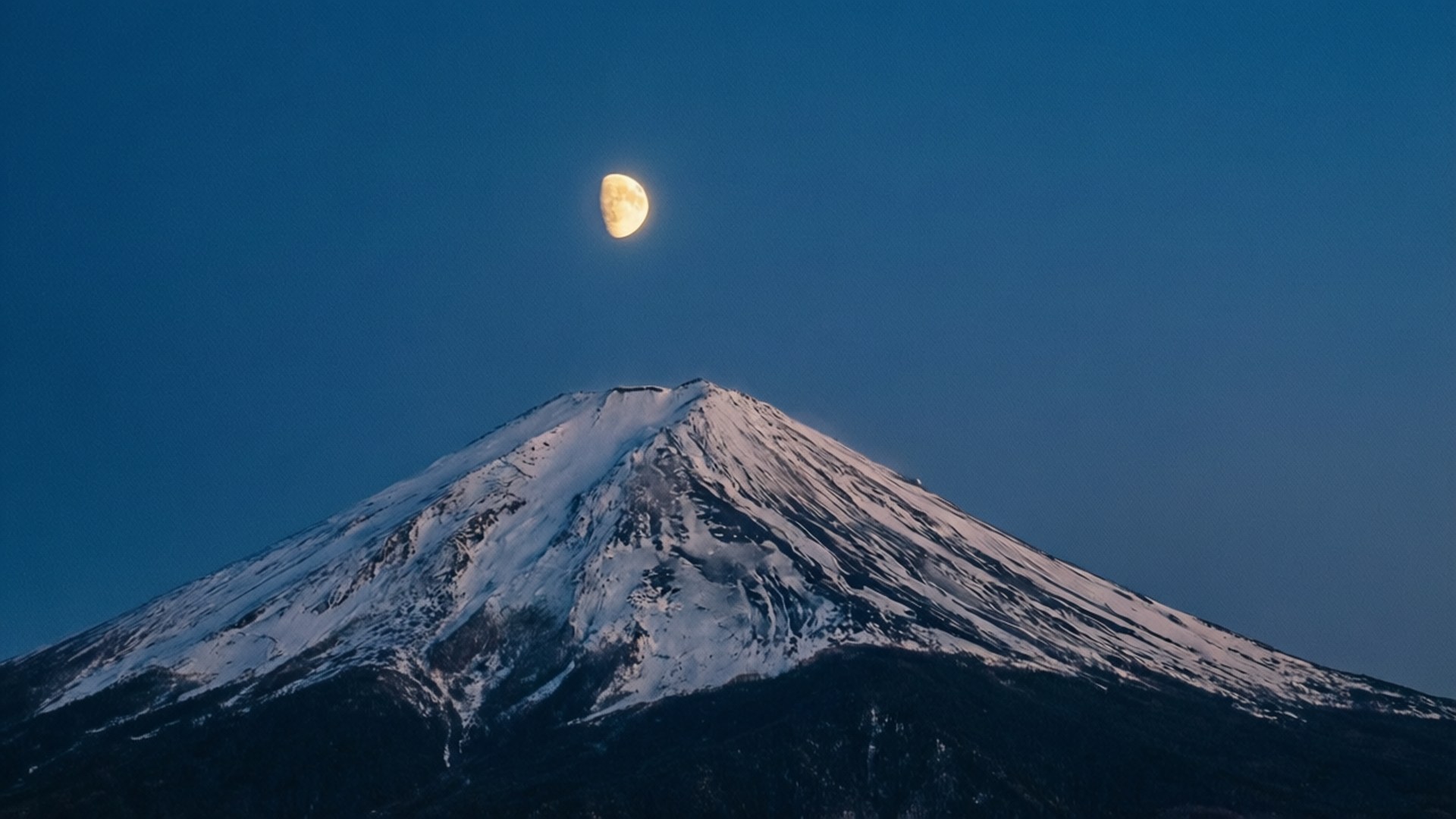 夜晚彎月下的白雪覆蓋富士山