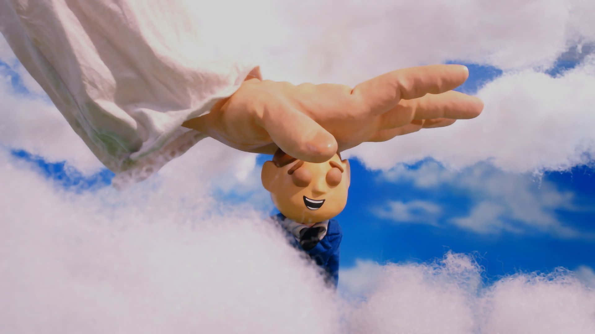 Moral Orel《Pleasure》劇情 壁紙 — 一隻巨手溫柔地托著一個微笑的卡通男孩，身穿西裝，漂浮在蓬鬆的白雲之上，背景是明亮的藍天。