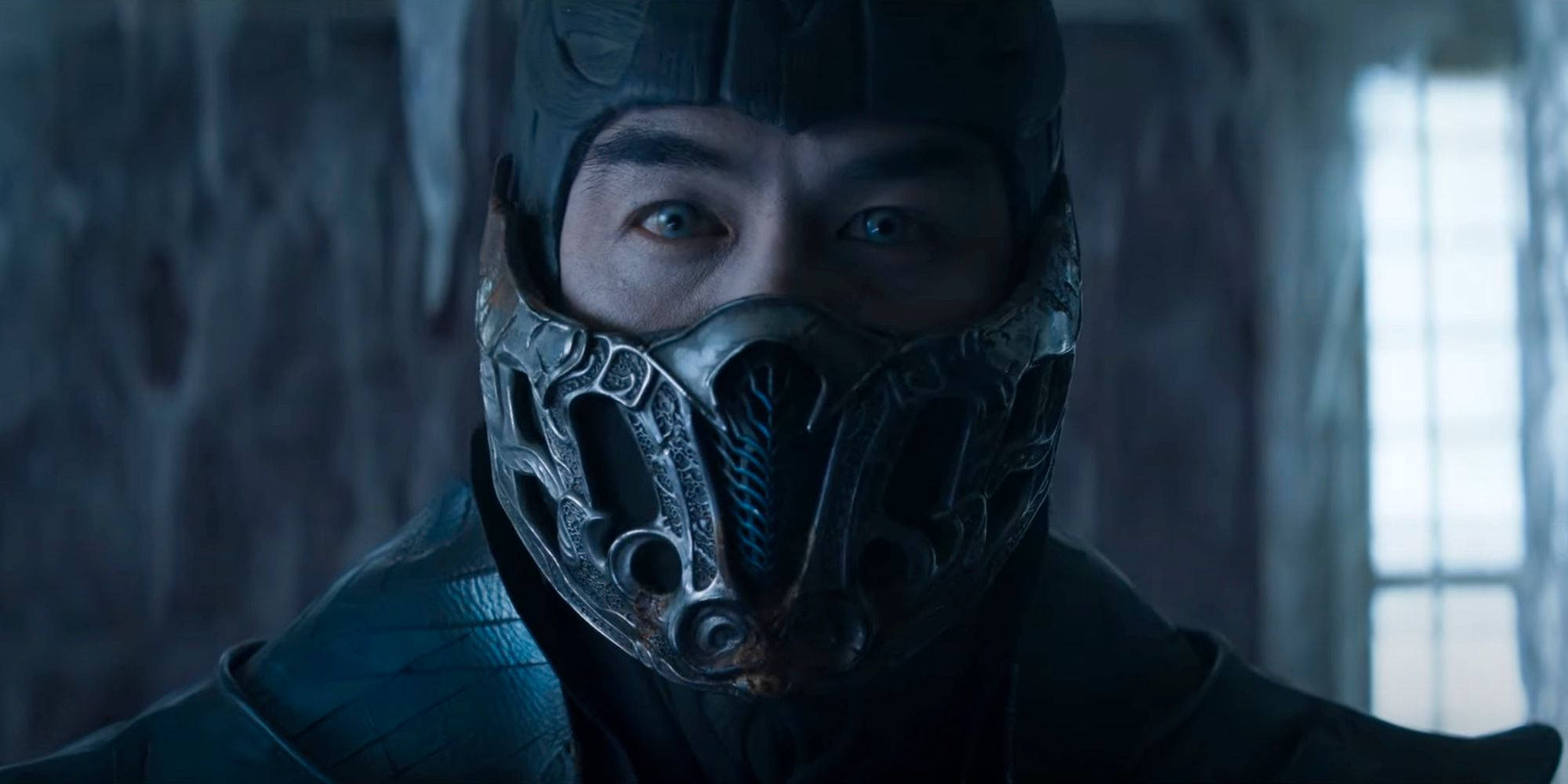 真人電影《Mortal Kombat》Sub-Zero 壁紙 — 一個帶有發光眼睛的威脅性蒙面戰士在昏暗的冰室中凝視。