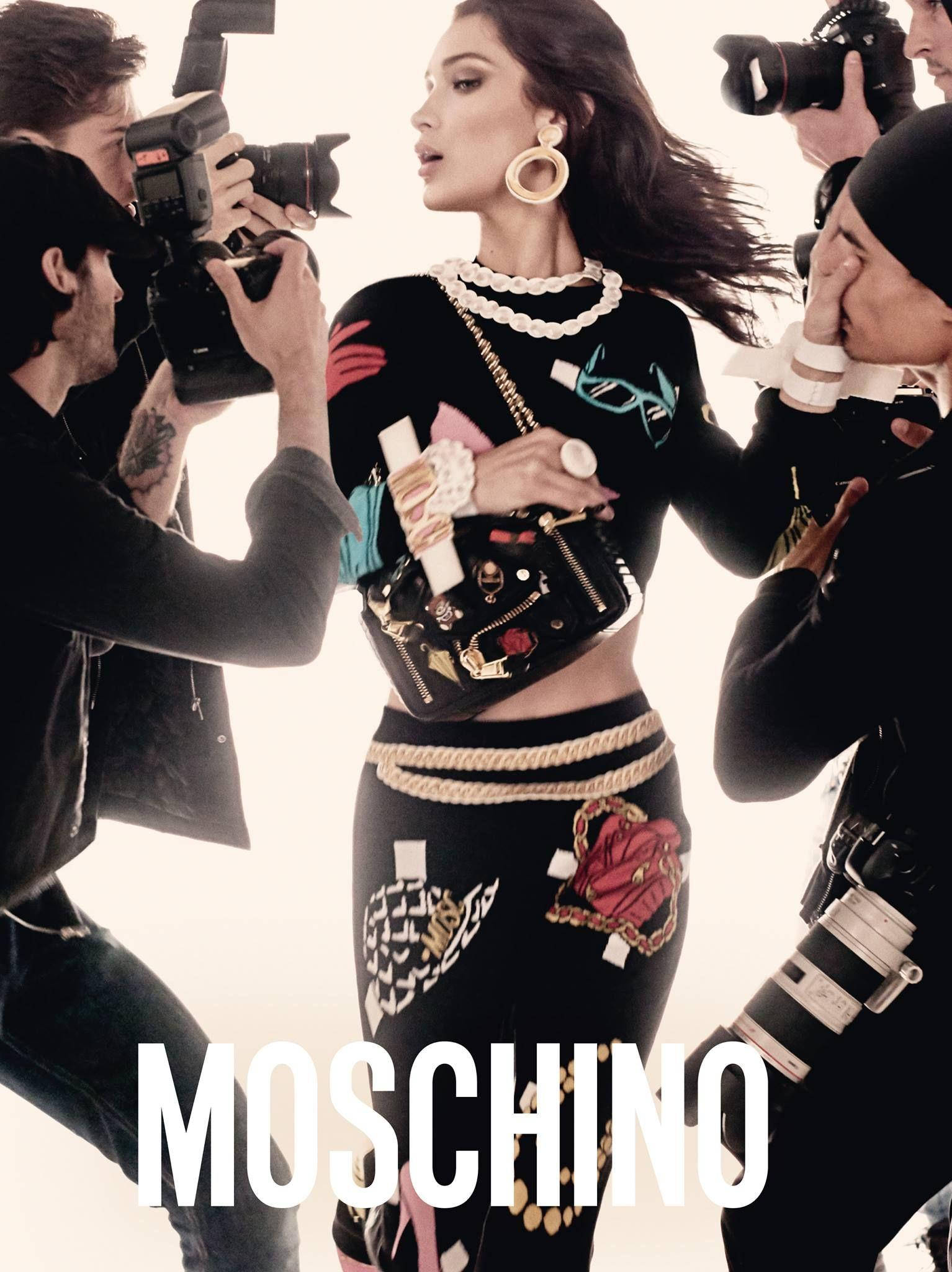 Moschino狗仔隊時尚 壁紙 — 模特兒身穿大膽的 Moschino 服裝，在充滿活力的時尚拍攝中被攝影師包圍擺姿勢。