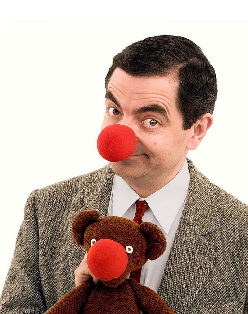  壁紙 — Mr Bean 戴著紅色小丑鼻，抱著一個同樣紅鼻子的泰迪熊，背景是純白色。