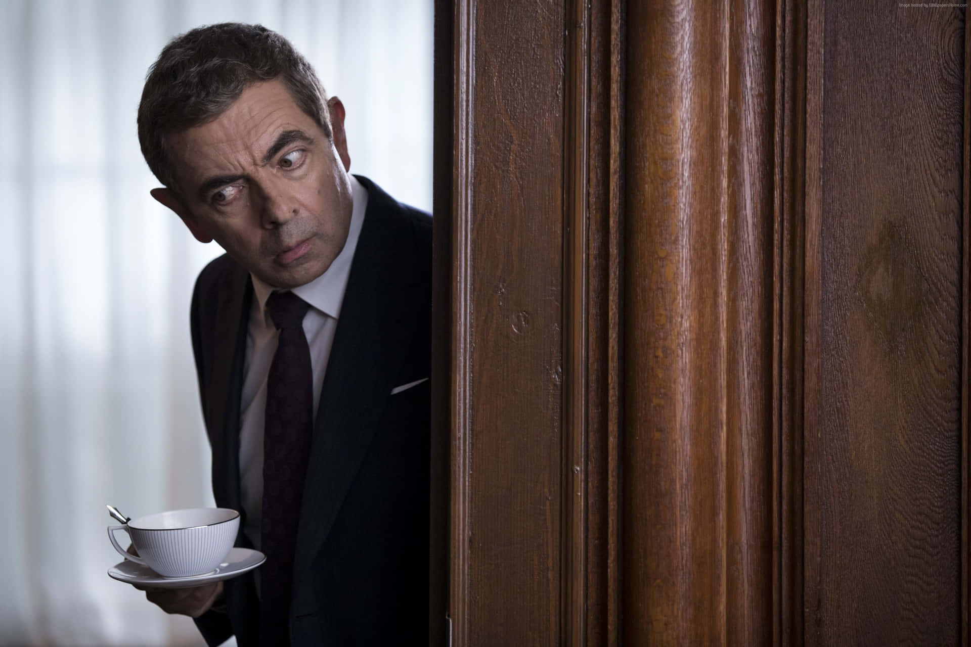  壁紙 — Mr Bean 緊張地從木門後面窺視，同時拿著茶杯和茶托。