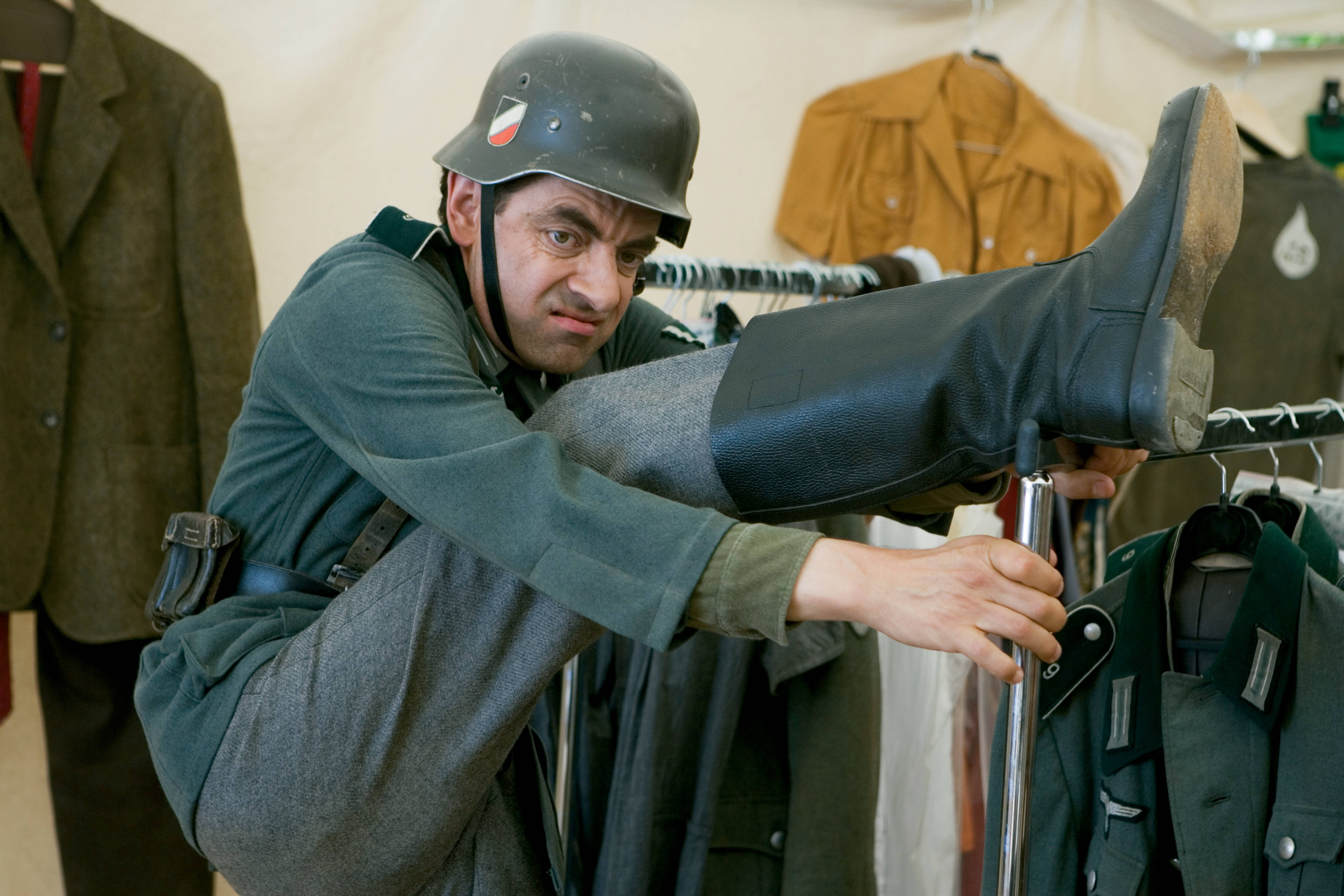 4K 桌布 壁紙 — Mr Bean 穿著二戰德國軍服，在帳篷內的衣架上平衡身體，試穿靴子。