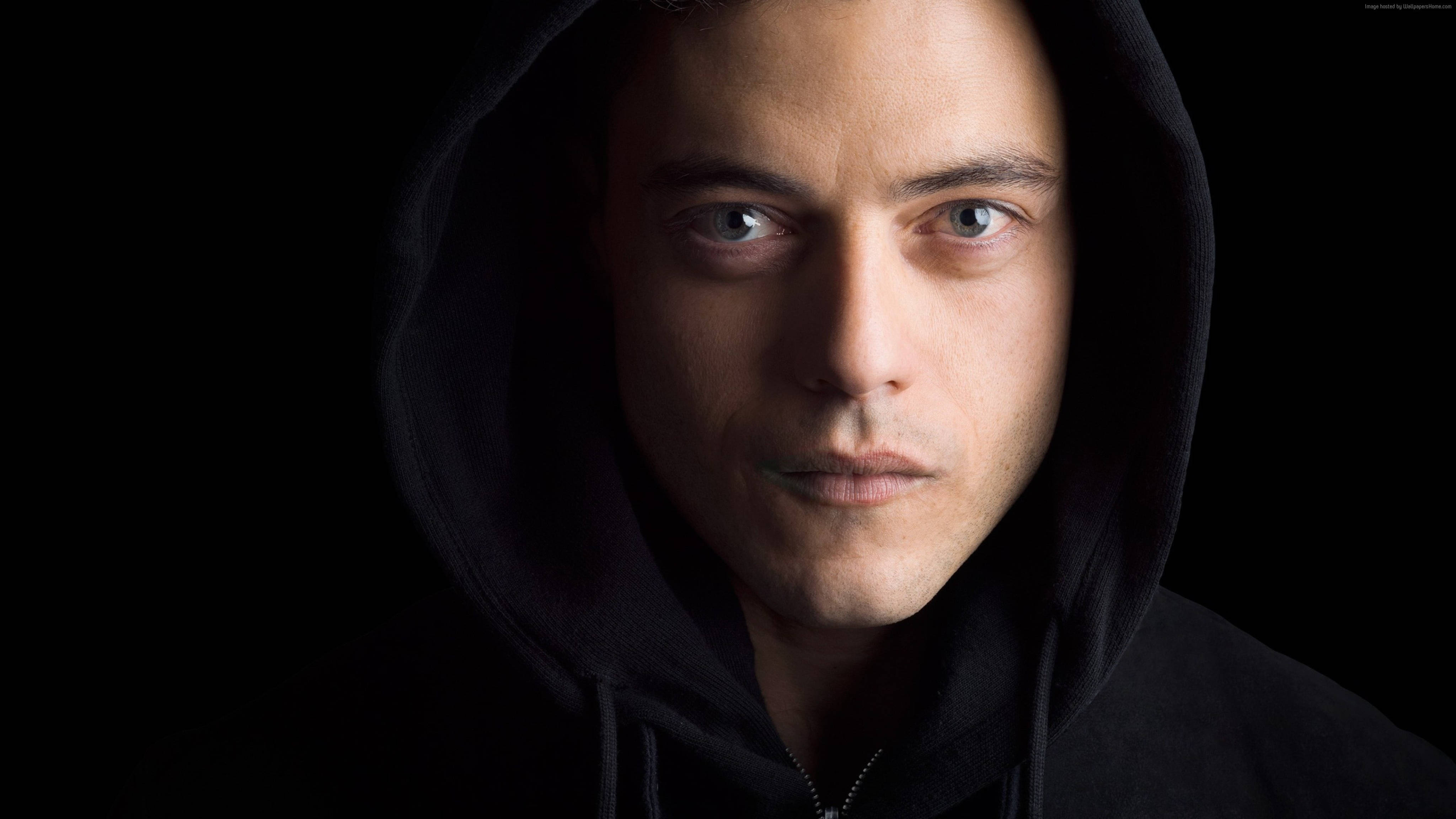 《Mr. Robot》戲劇攝影藝術 壁紙 — 一個穿著黑色連帽衫的男人在黑暗背景下，戲劇性的燈光突出他的臉，他凝視著。