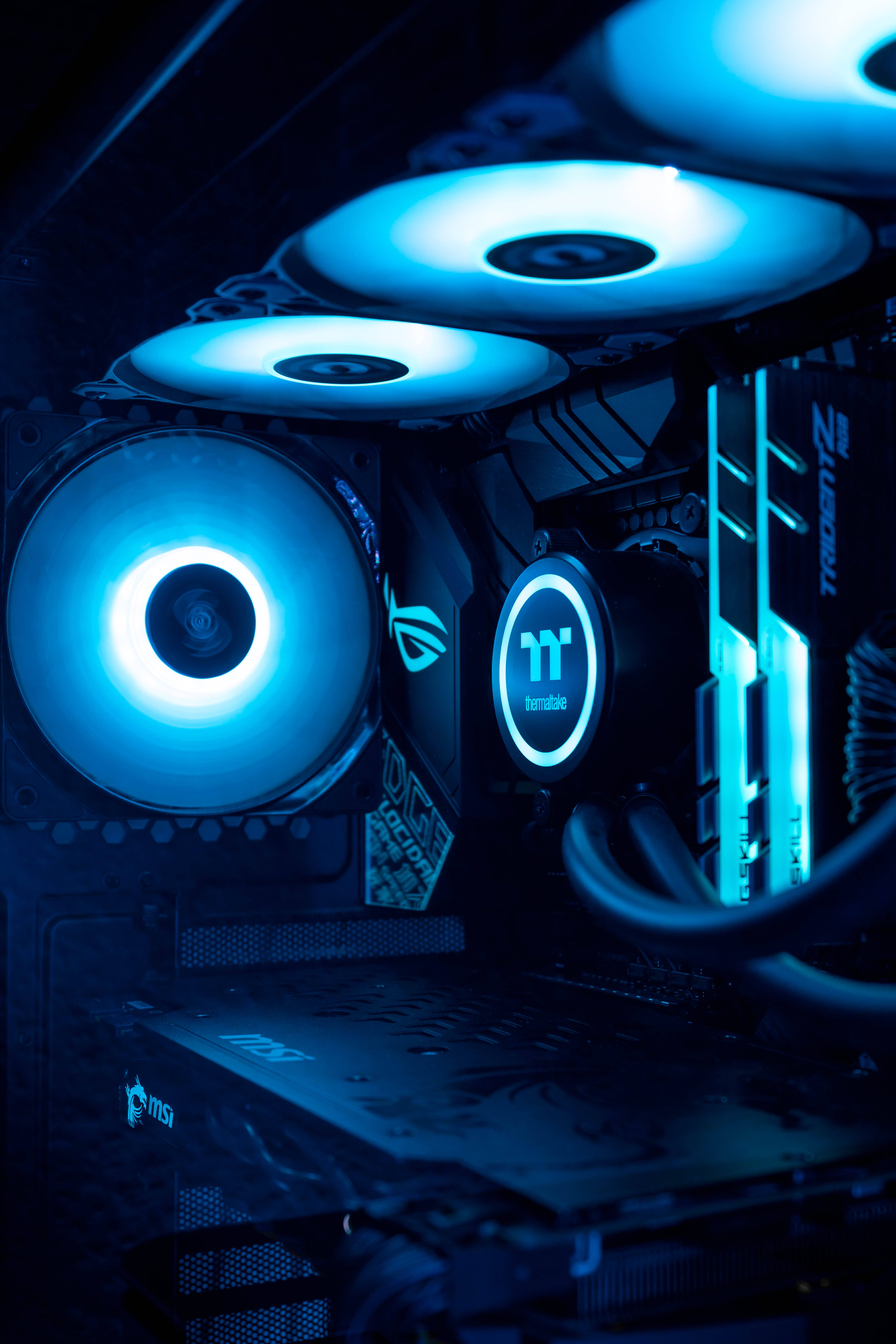 藍色 MSI 遊戲電腦組件 壁紙 — 高端遊戲電腦內部特寫，沐浴在風扇和組件發出的冷藍色LED燈光中。