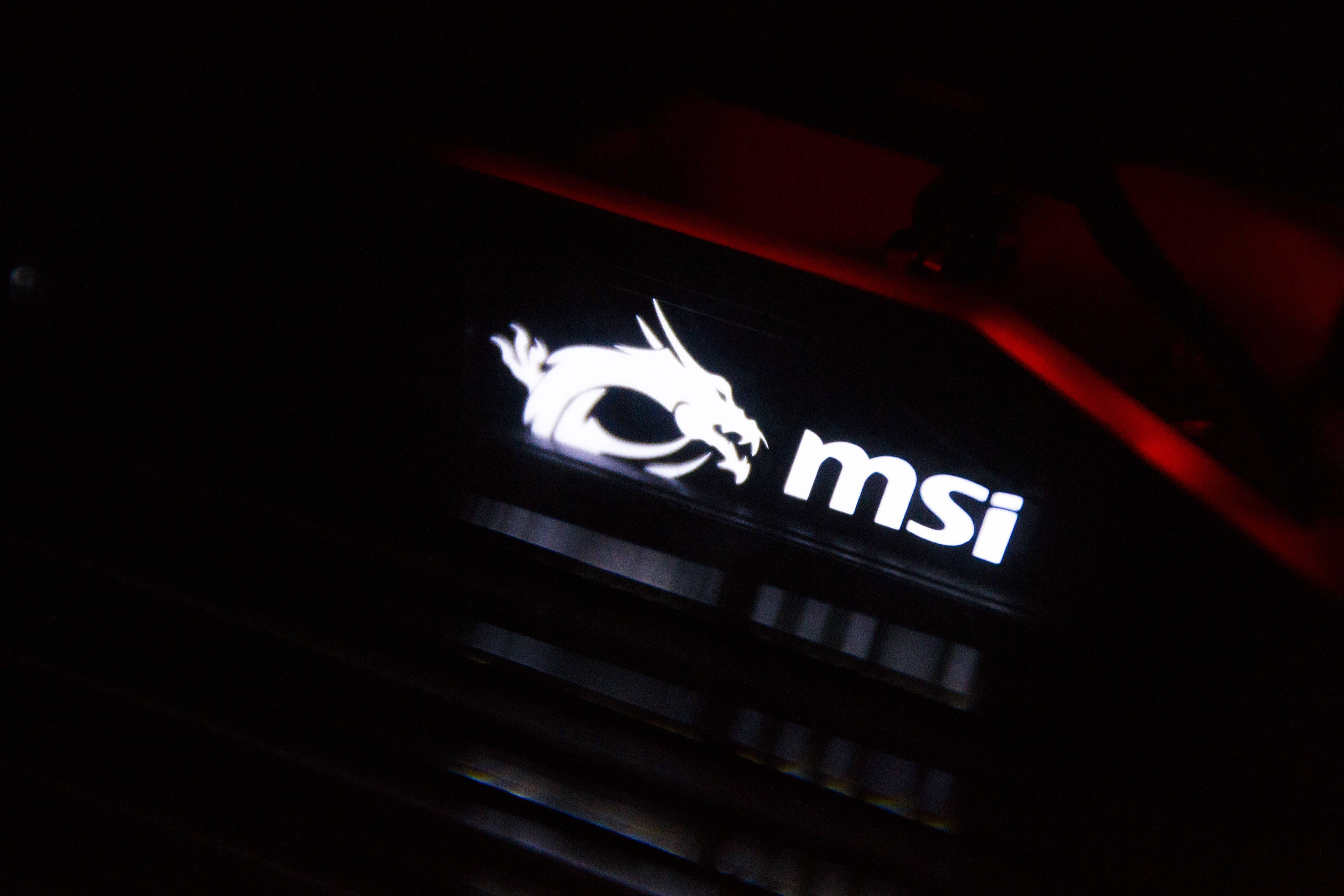 MSI 4K 白色龍 壁紙 — 暗色電腦機箱上帶有紅色環境燈光的發光白色MSI龍標誌和文字。