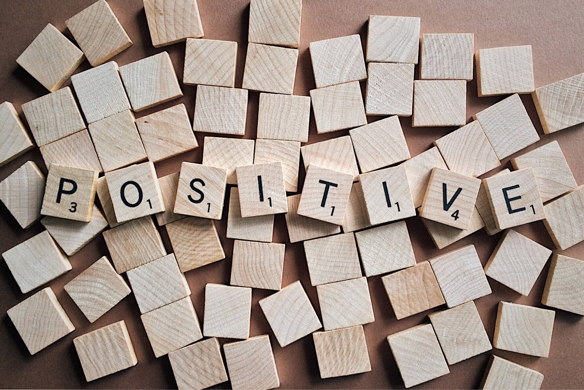 在棕色背景上拼出「positive」的 Scrabble 字母磚