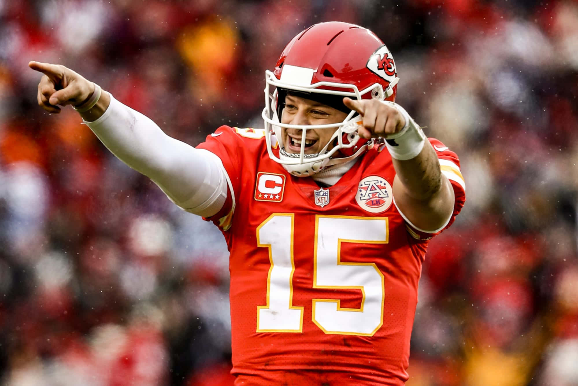 MVP 且為堪薩斯城酋長隊四分衛的 Pat Mahomes 壁紙 — 一位微笑的美式足球四分衛身穿紅色15號球衣，在雨中比賽中勝利地指向遠方。