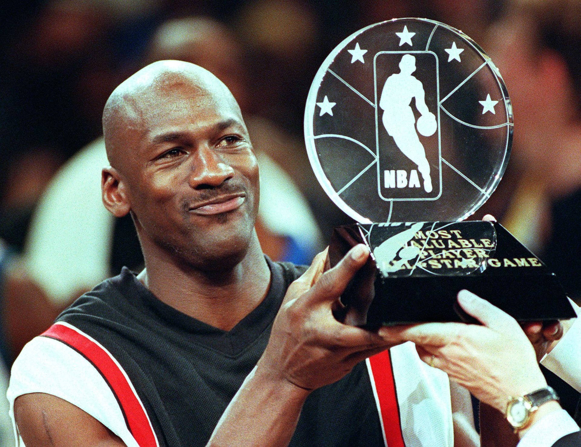MVP 迈克尔·乔丹 壁紙 — 米高佐敦在擠滿人的場館中自豪地微笑，手持他的NBA全明星賽最有價值球員獎盃。