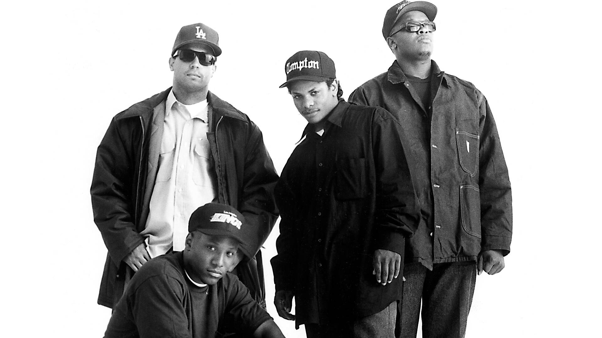 N.W.A. 1990年《洛杉磯時報》專訪照 壁紙 — 四位戴帽子和穿外套的男士在純白背景下自信地擺姿勢，呈現經典黑白肖像。