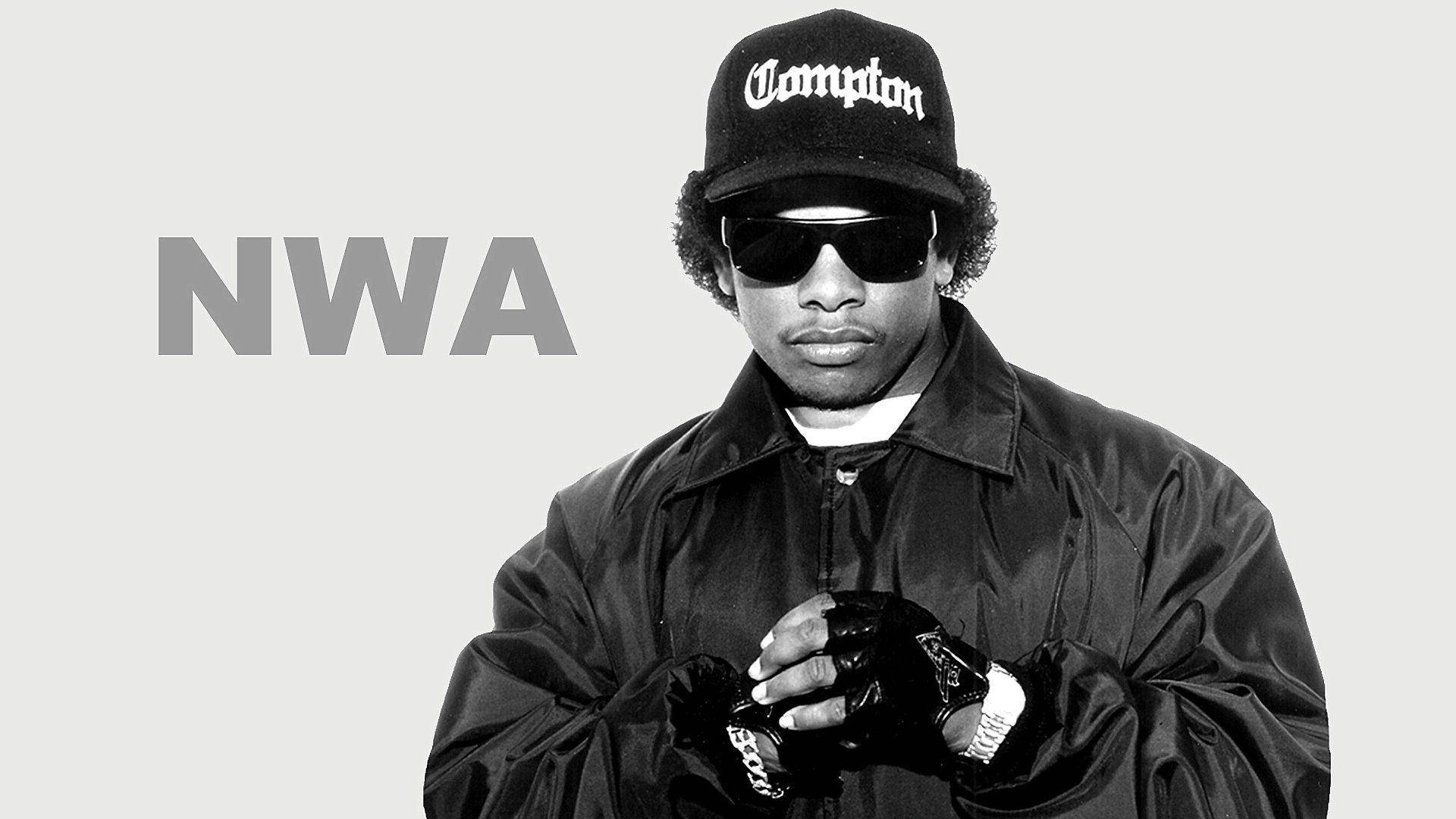 N.W.A.成員Eazy-E酷炫Gangsta饒舌歌手 壁紙 — 一個男人的黑白肖像，戴著Compton帽子、太陽眼鏡和旁邊有NWA文字的夾克。