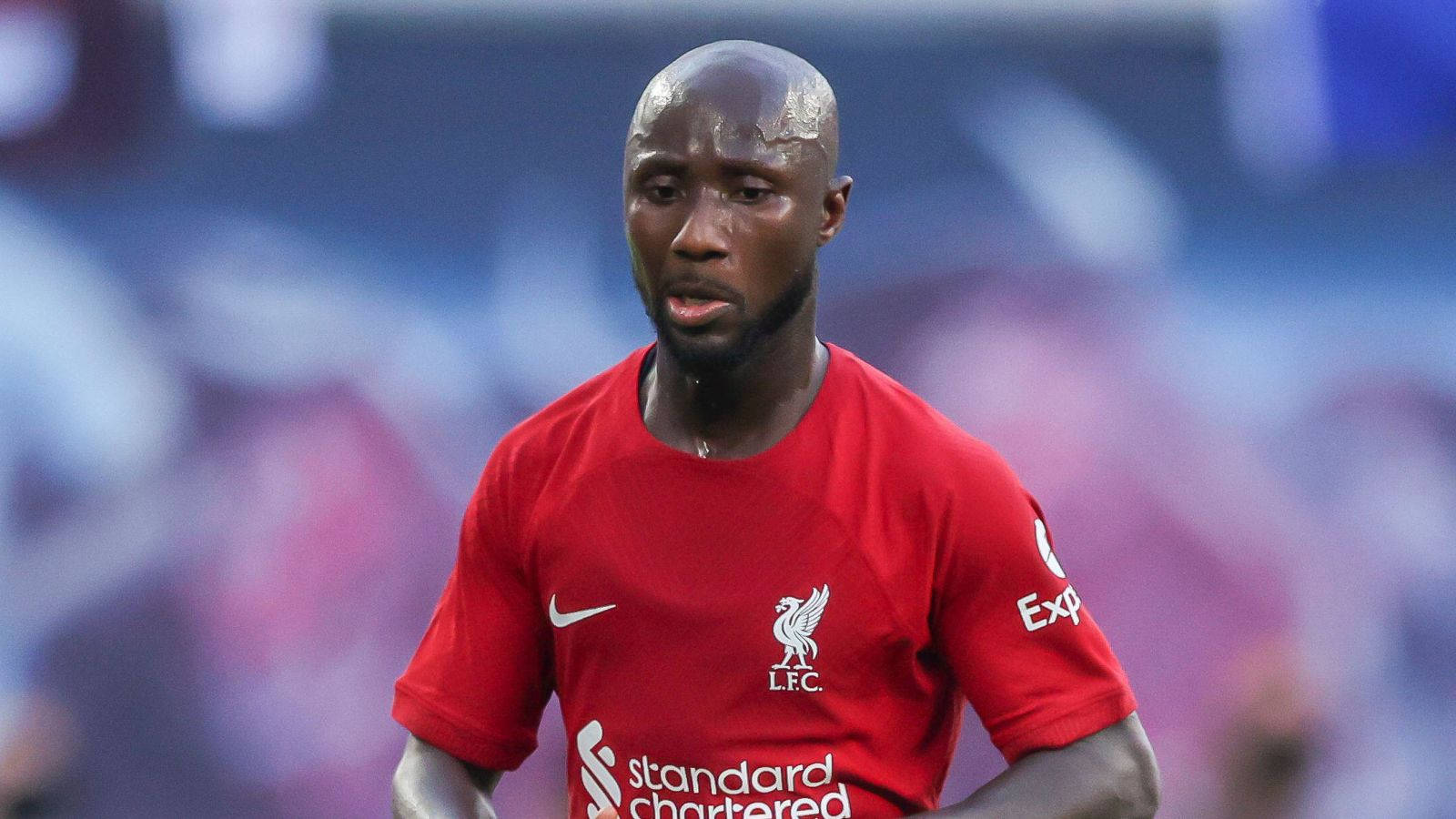 Naby Keita 混淆表情 壁紙 — 一名專注的足球員身穿紅色利物浦球衣，比賽期間額頭上的汗水閃閃發光。