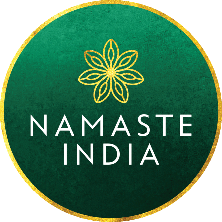 Namaste印度問候標誌 壁紙 — 一個圓形綠色徽章，帶有金色邊框，中央有一個金色花卉標誌，並以白色字體寫有「NAMASTE INDIA」。