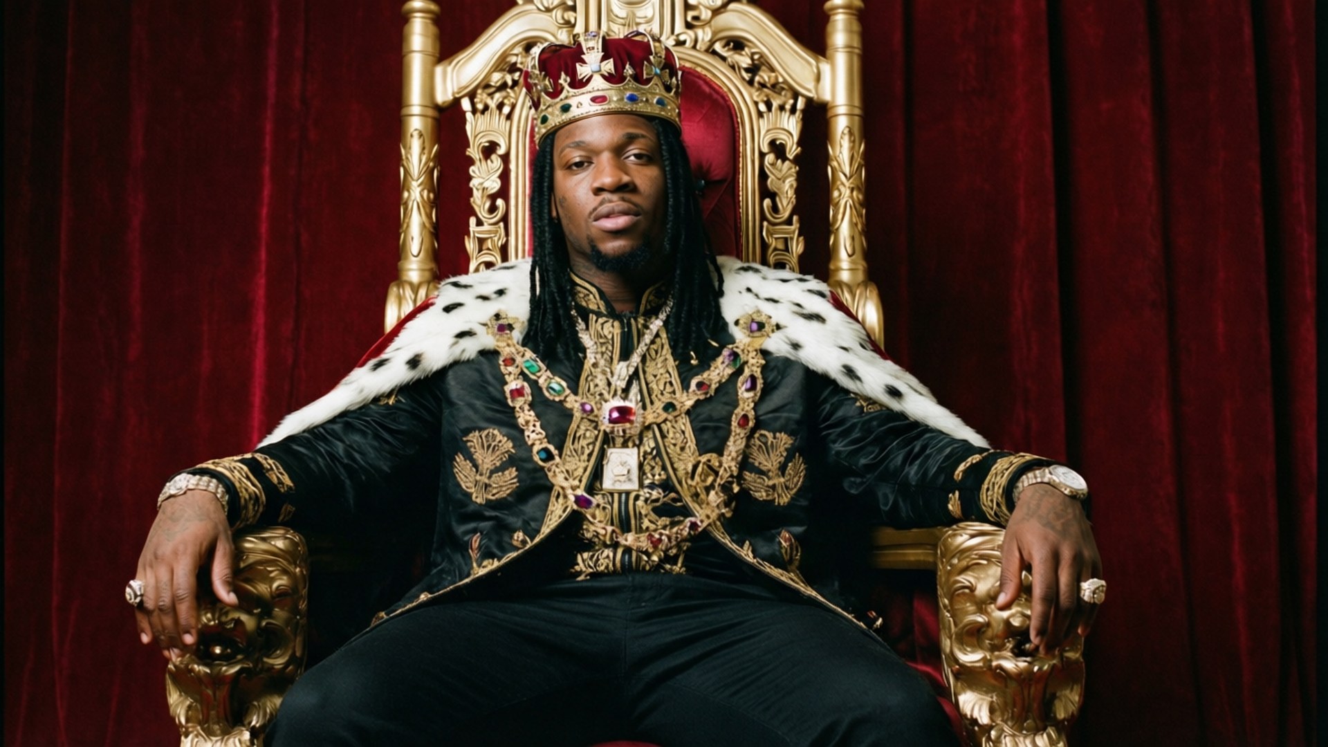 King of Memphis 壁紙 — 一名留著辮子的男子威嚴地坐在金色王座上，戴著鑲有寶石的王冠和華麗的黑色長袍，背景是紅色天鵝絨窗簾。