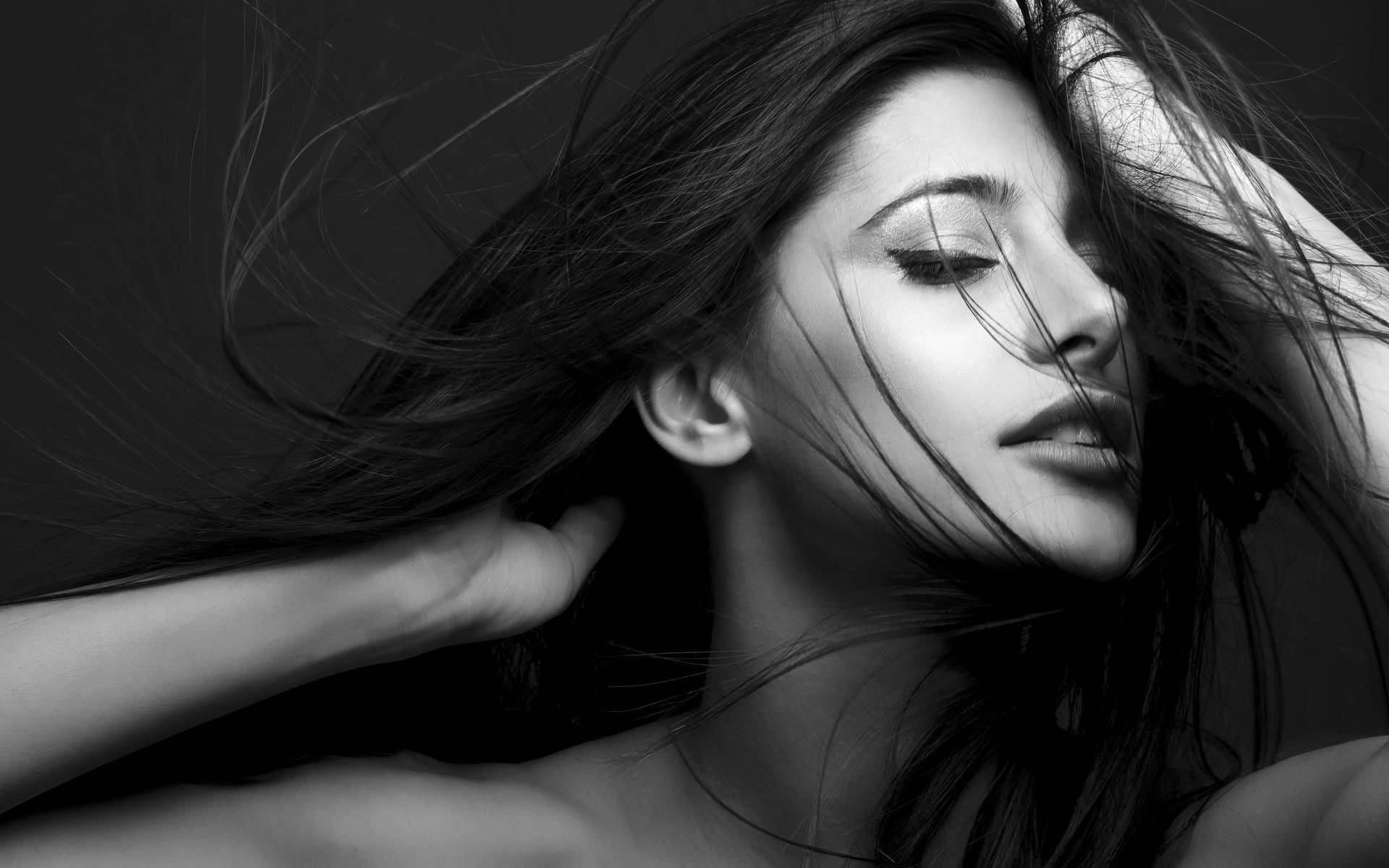 一位長髮飄逸的女性輕輕觸碰臉龐的黑白肖像。