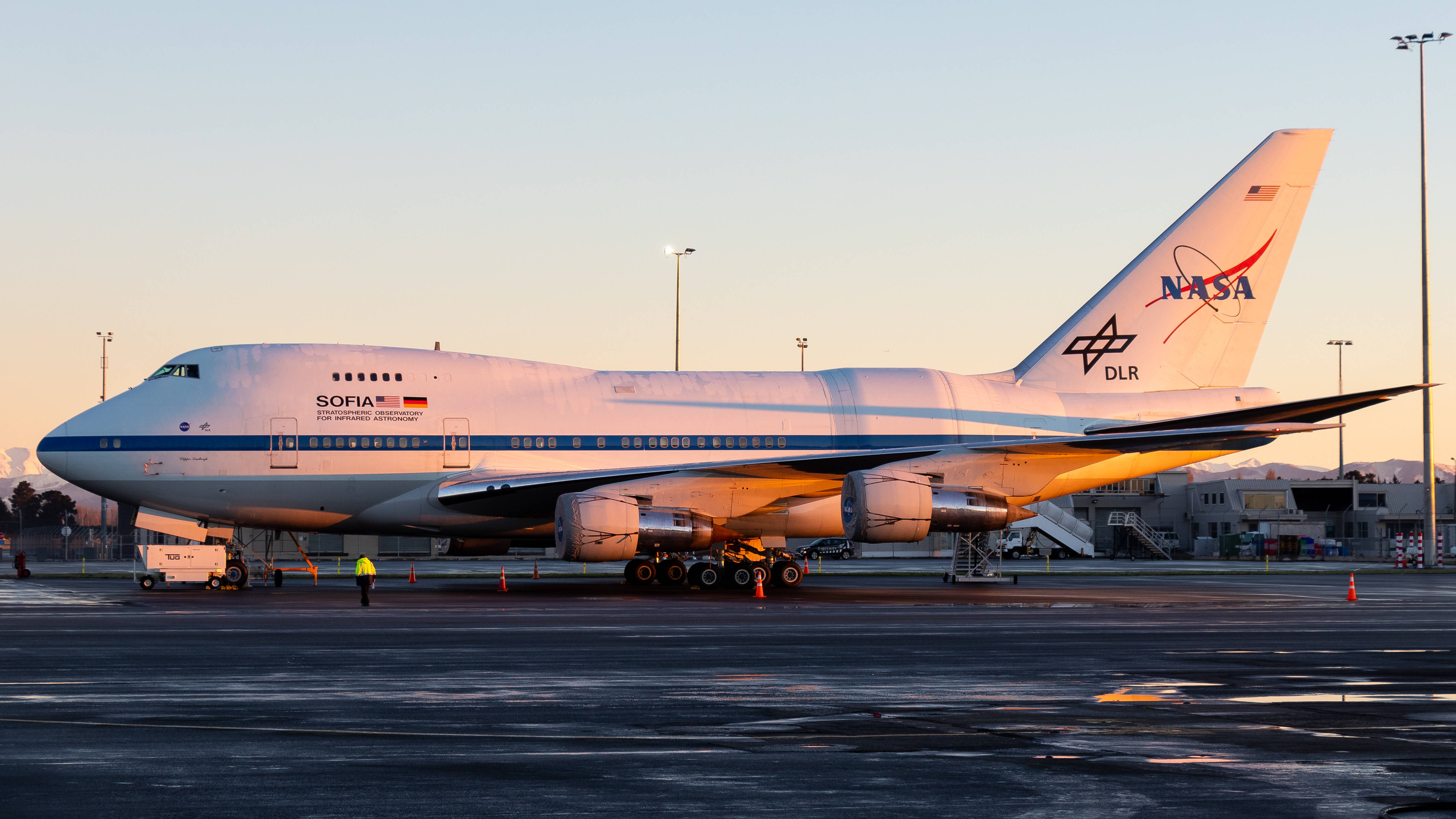 NASA Sofia 航空航天 壁紙 — 一架NASA SOFIA空中天文台飛機在黃金時段停泊在機場停機坪上，溫暖的光線投下長長的影子。