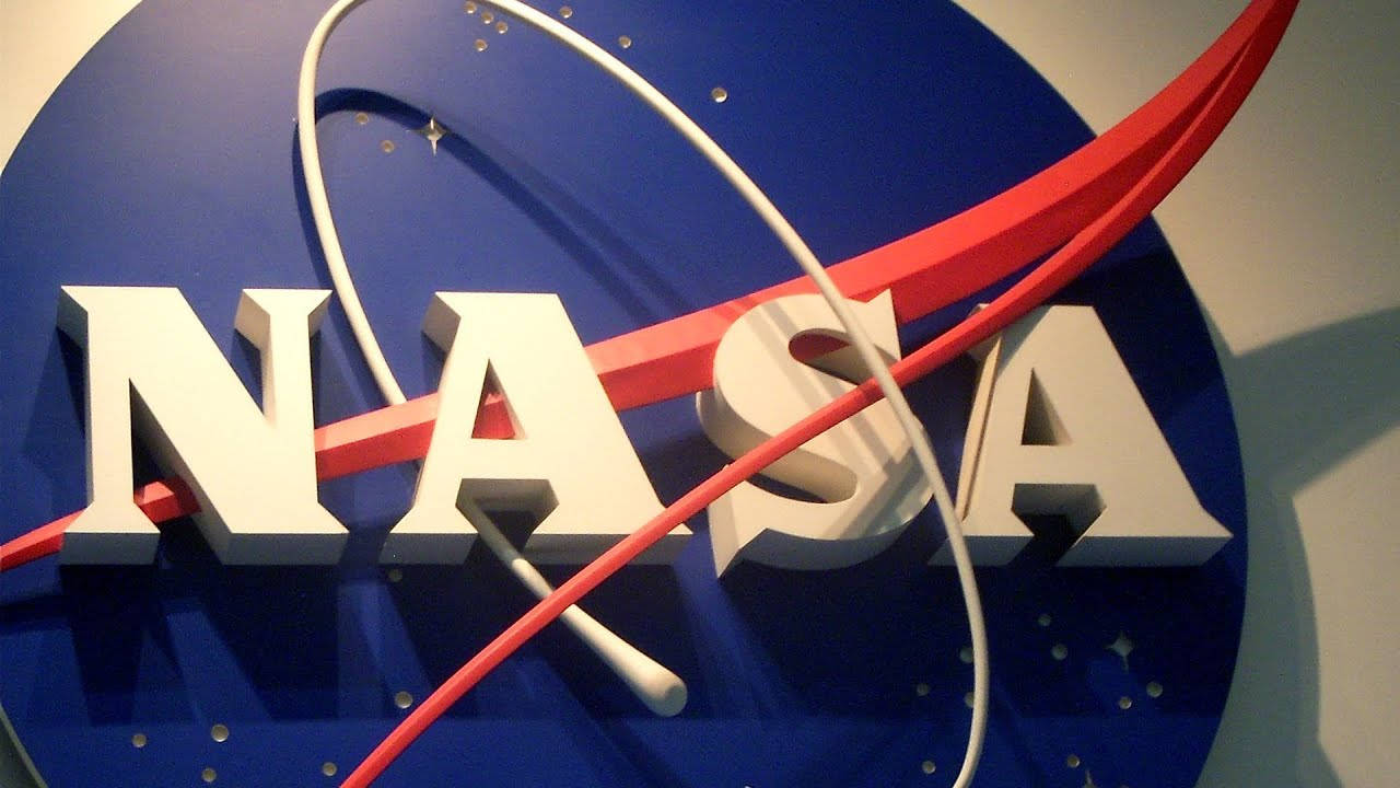 NASA休士頓標誌招牌 壁紙 — 一個三維NASA標誌的特寫，白色字母、紅色和白色曲線在藍色圓形背景上。