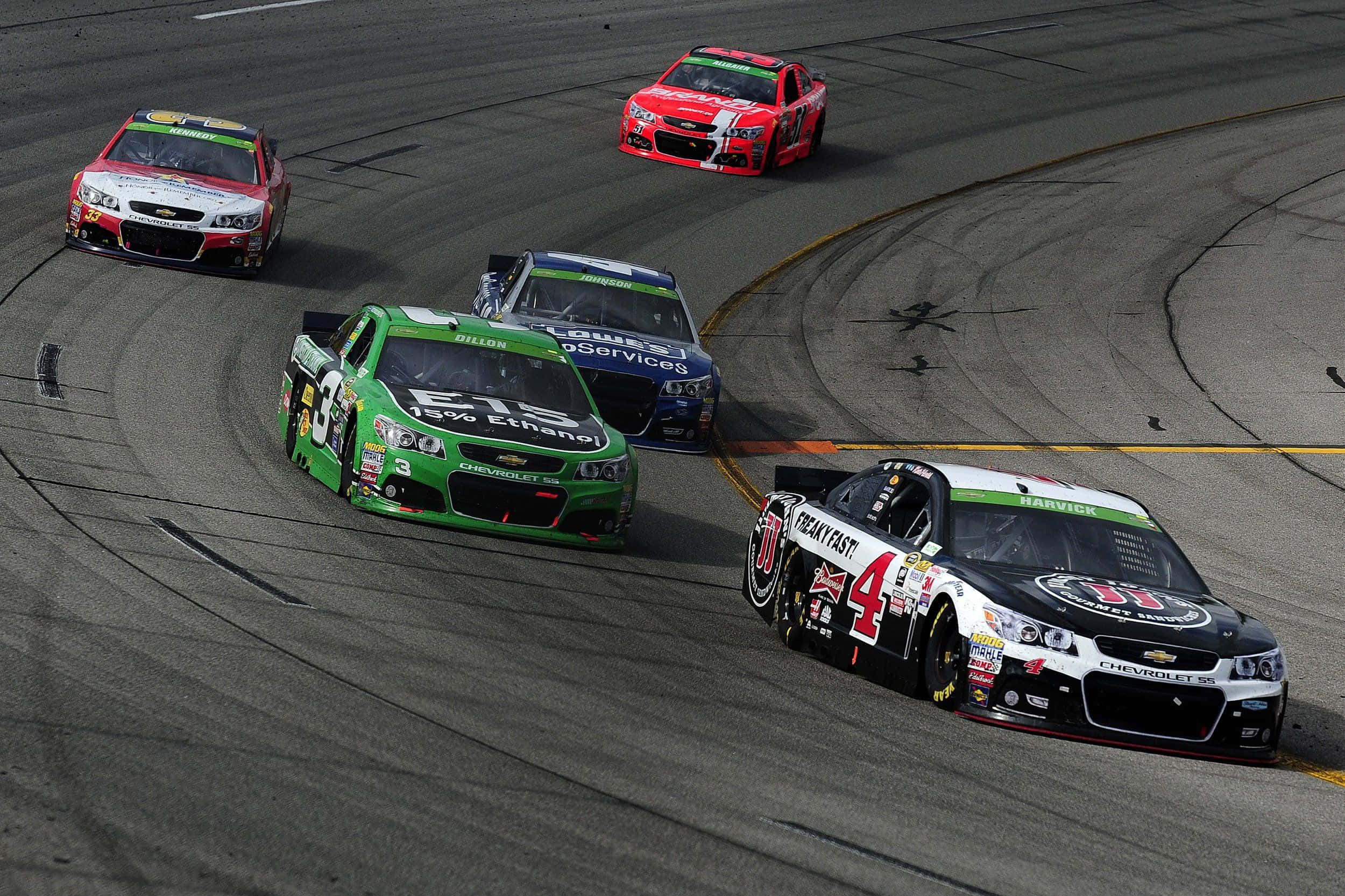 親身感受NASCAR的高速競賽 壁紙 — 五輛NASCAR賽車在陽光普照的瀝青賽道上激烈爭奪位置，輪胎痕跡清晰可見。