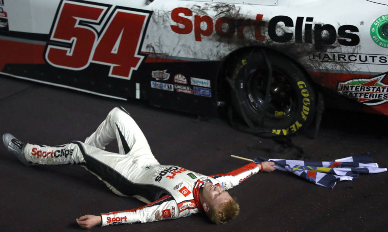 NASCAR車手在撞車後手持格仔旗在賽道上慶祝勝利。