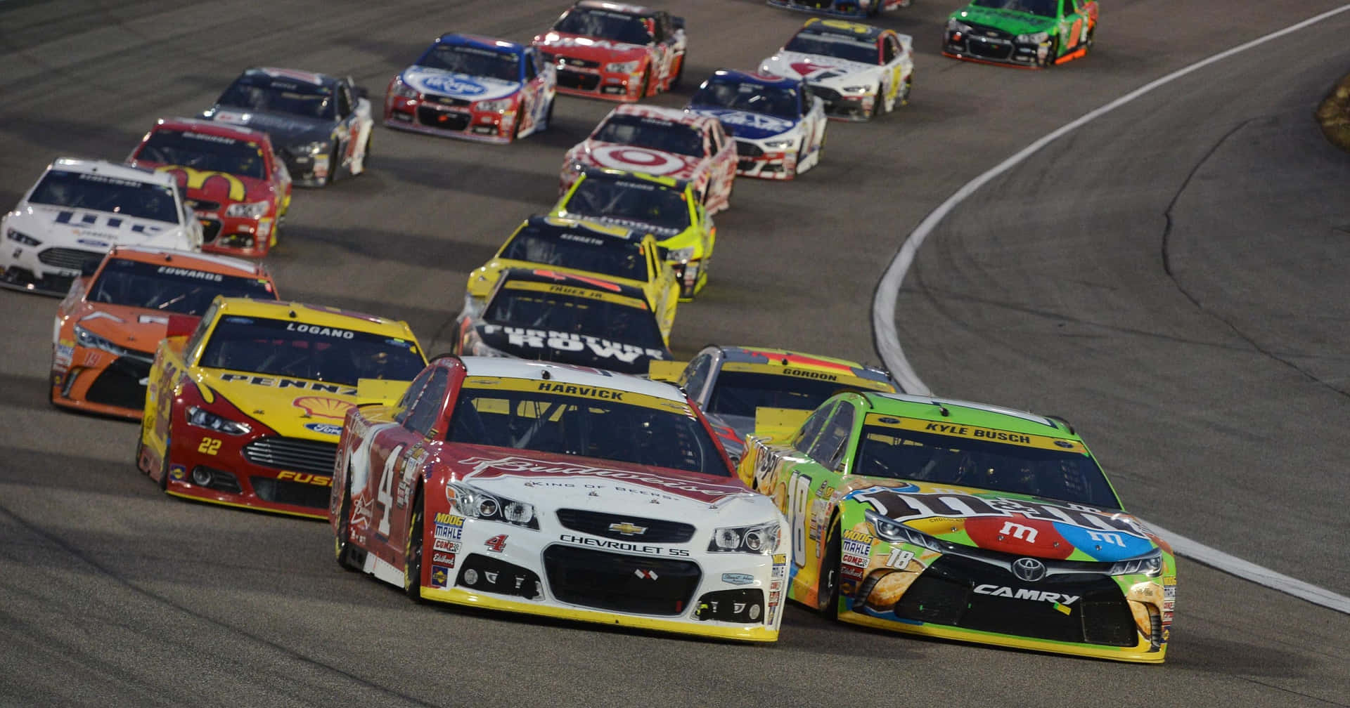 NASCAR賽車在明亮的燈光下夜間在賽道上高速飛馳。