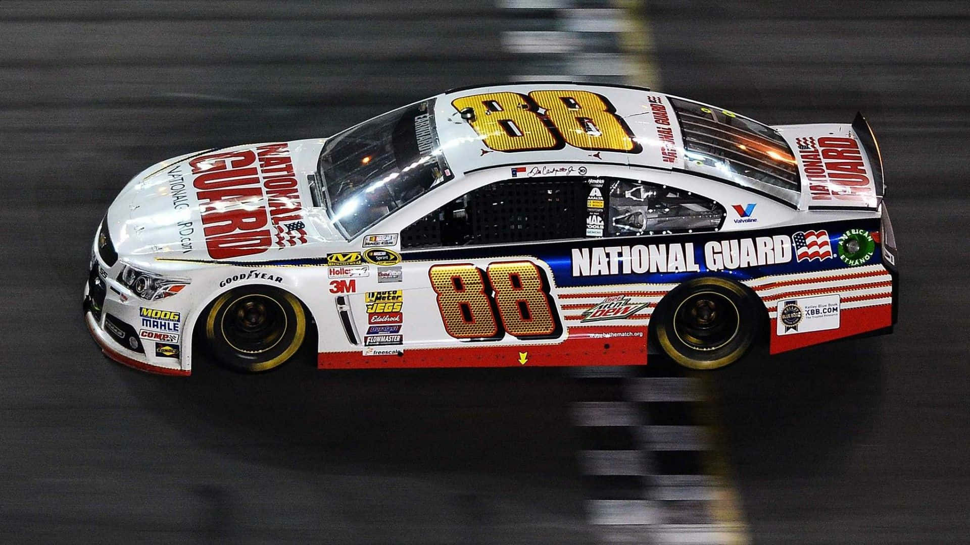 一輛編號88的NASCAR賽車在夜間賽道上飛馳。