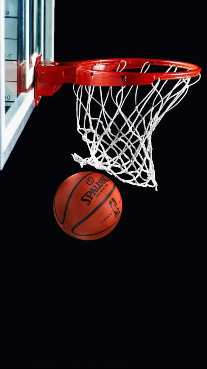 準備迎接NBA賽季，擁有最新手機！ 壁紙 — 一個 Spalding 籃球懸掛在紅色籃框正下方，背景為純黑色。