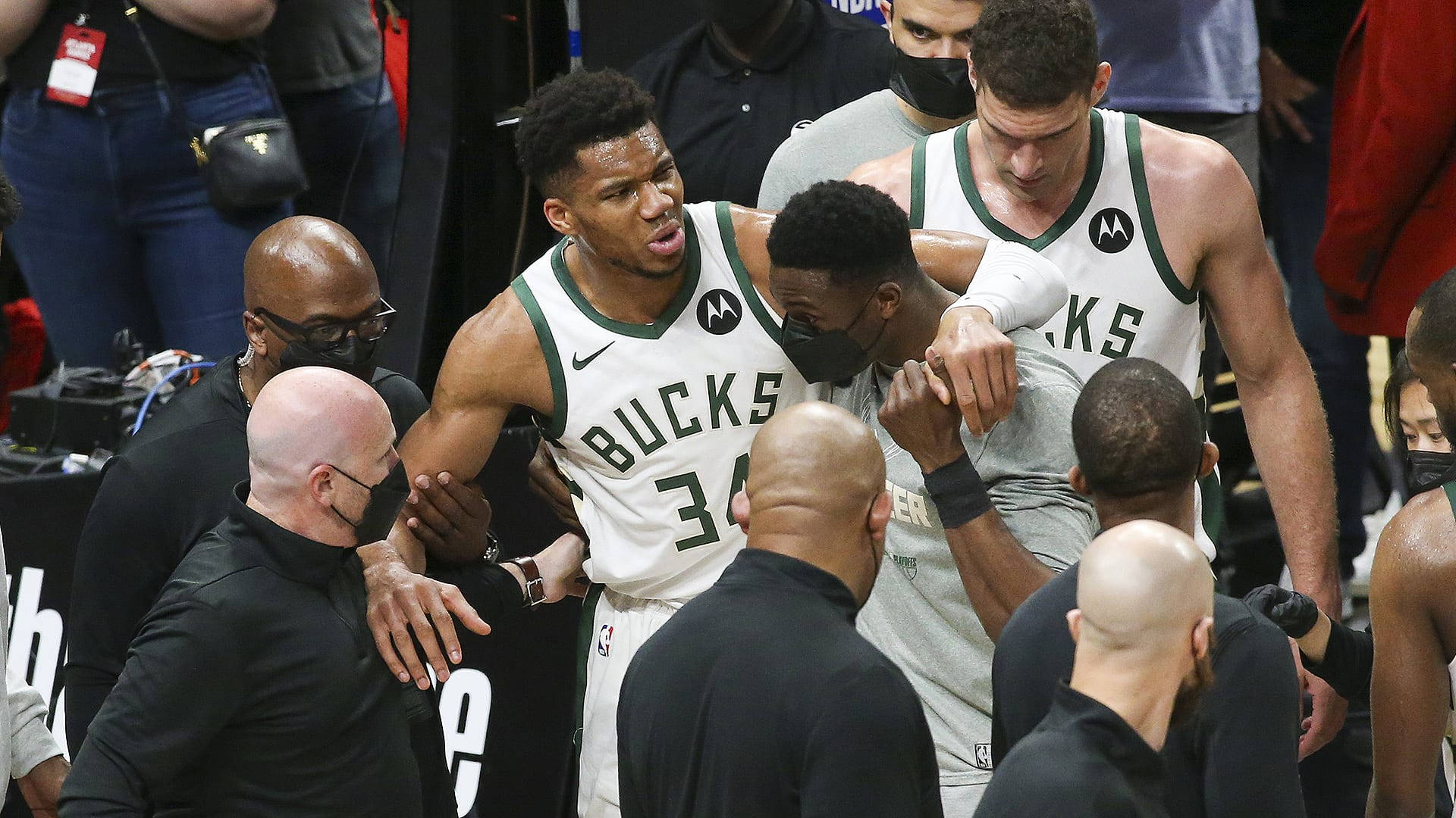 NBA總決賽的激烈時刻：球員為冠軍全力以赴 壁紙 — 身穿密爾沃基公鹿隊球衣的籃球運動員在球場上緊密聚集，周圍是教練和工作人員。