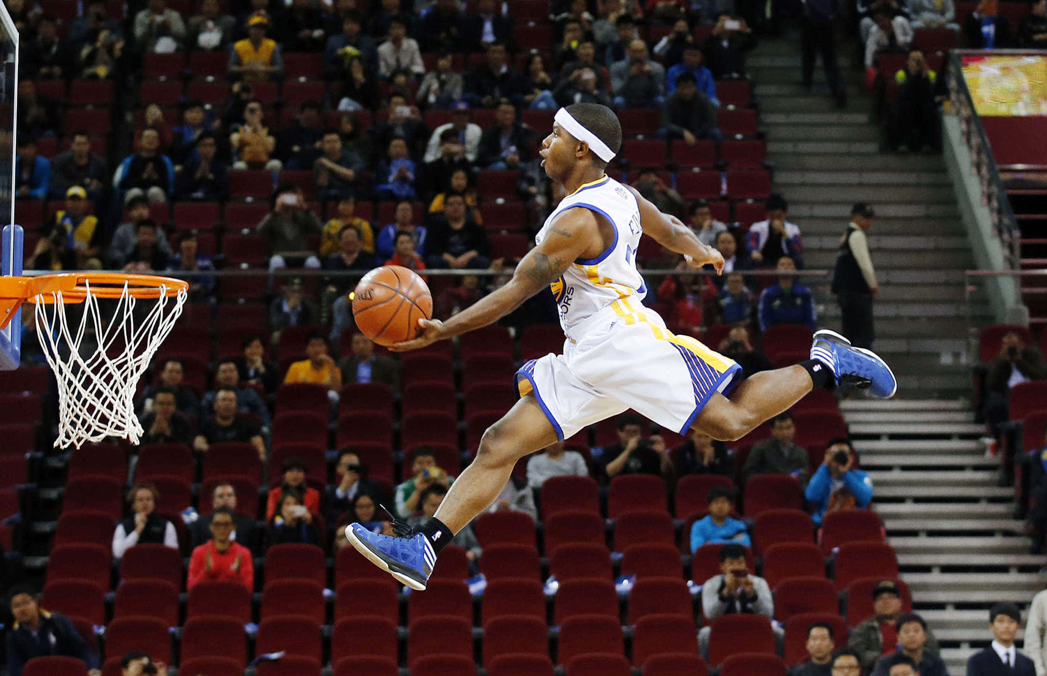 搞笑NBA高跳圖片 壁紙 — 一名身穿白色和藍色球衣的籃球運動員在比賽中全神貫注地跳向籃框。