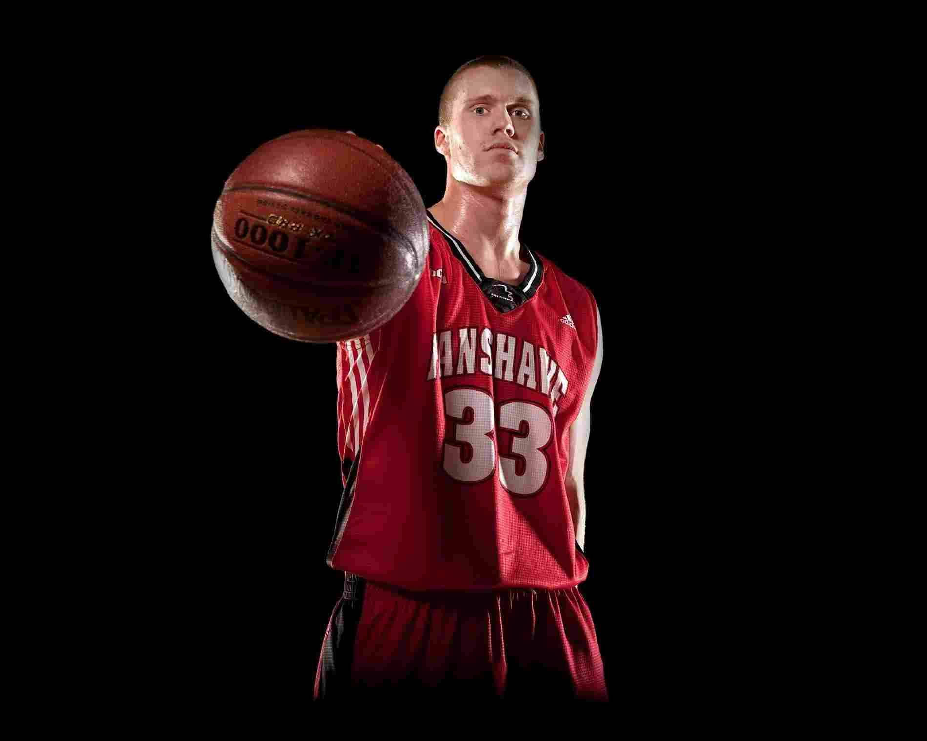 酷炫NBA球員 壁紙 — 一名身穿紅色球衣的籃球運動員在強烈的黑色背景下，以戲劇性的燈光持球。