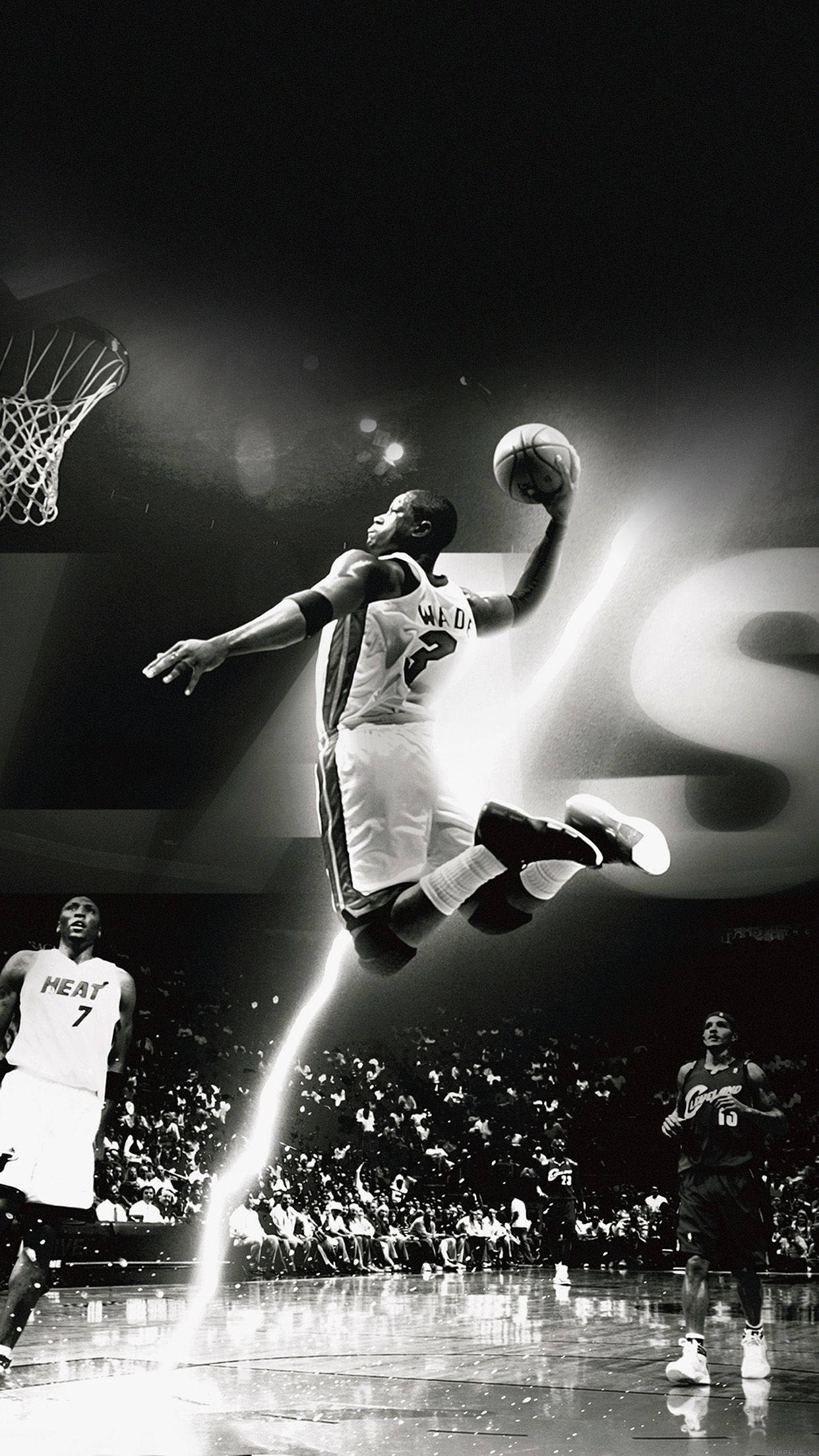 NBA iPhone 德懷恩·韋德 迈阿密熱火隊灌籃 壁紙 — 一位籃球運動員在半空中飛翔，以黑白畫面呈現，戲劇性的聚光燈光束劃過場館，正在灌籃。