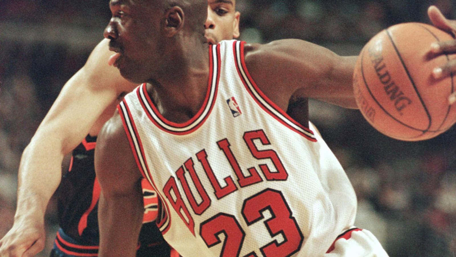 獲取傳奇NBA球員邁克爾·喬丹的經典球衣 壁紙 — 米高佐敦身穿芝加哥公牛隊球衣，在關鍵籃球比賽中專注地越過防守球員。