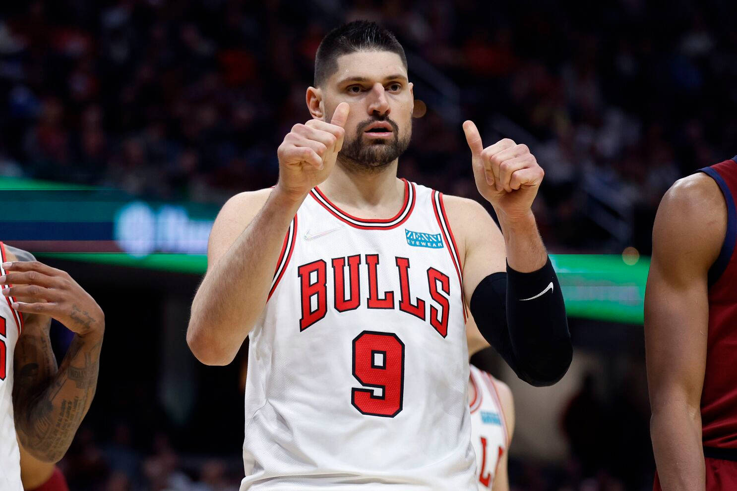 NBA 球員尼古拉·武切維奇芝加哥公牛隊雙拇指上揚 壁紙 — 一位身穿白色9號球衣的芝加哥公牛隊籃球運動員在比賽中雙手指向上方。
