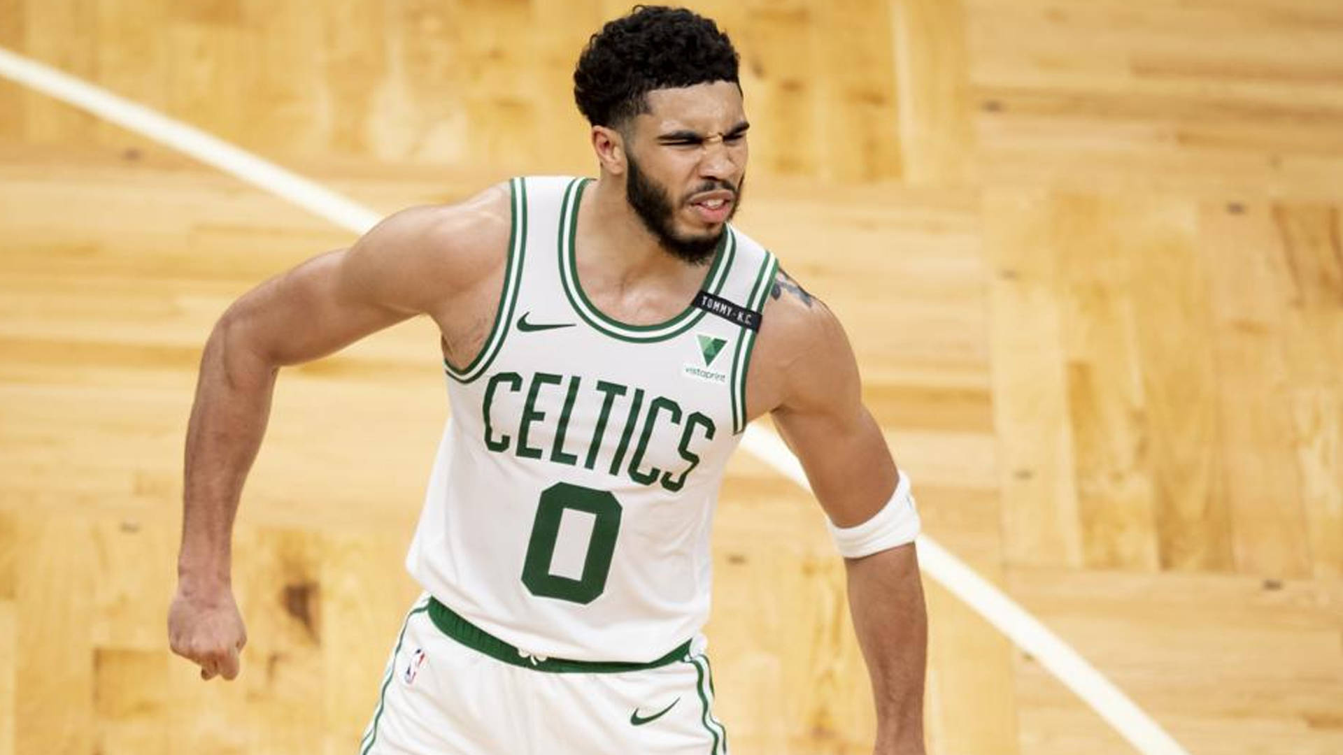 NBA總決賽凱爾特人隊傑森·塔圖姆 壁紙 — 一名身穿白綠球衣的波士頓塞爾特人籃球運動員在木地板上充滿決心地激烈奔跑。